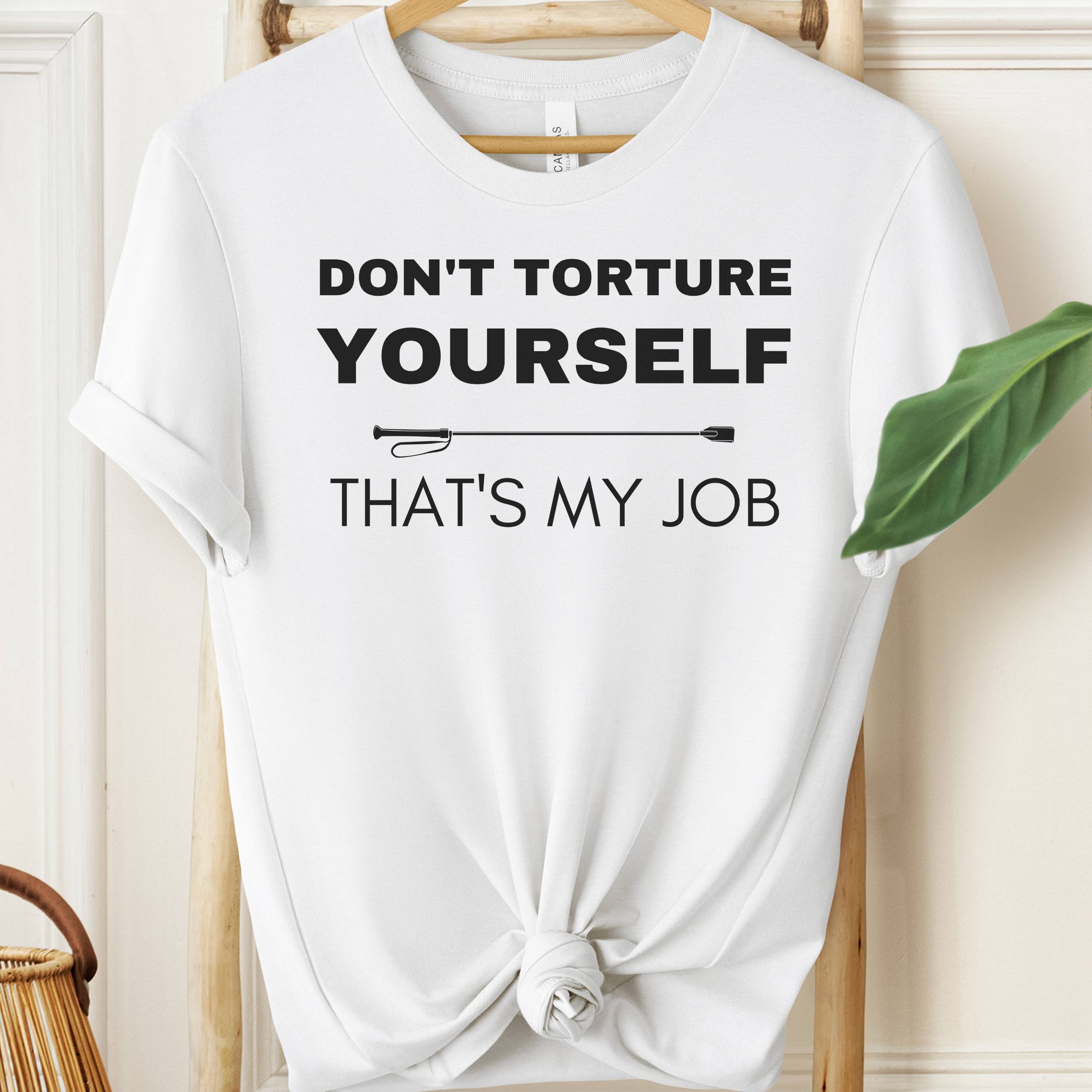 White t-shirt with text 'Don't torture yourself, that's my job' on a hanger.