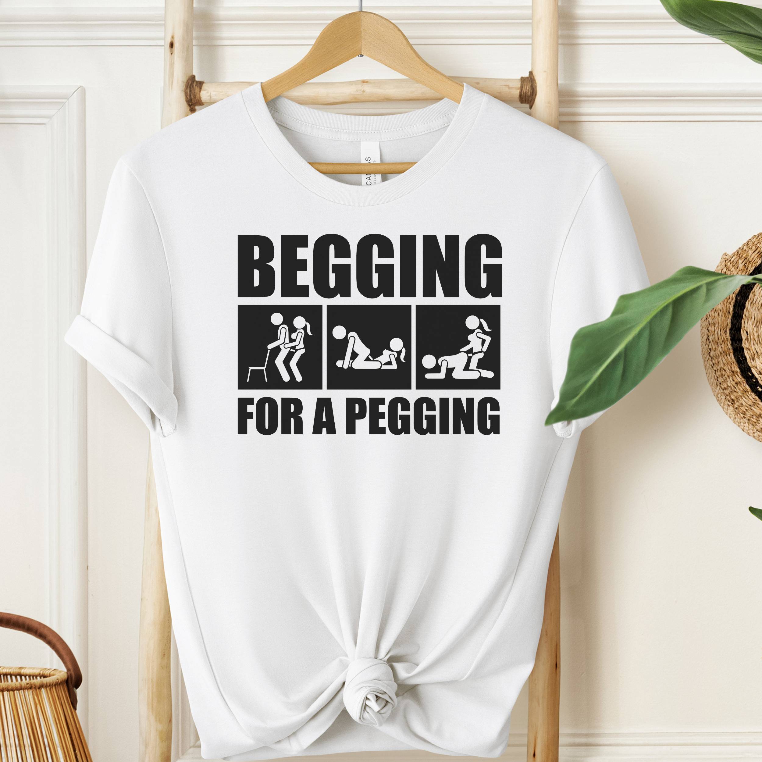 White t-shirt with graphic text on a hanger against a neutral background