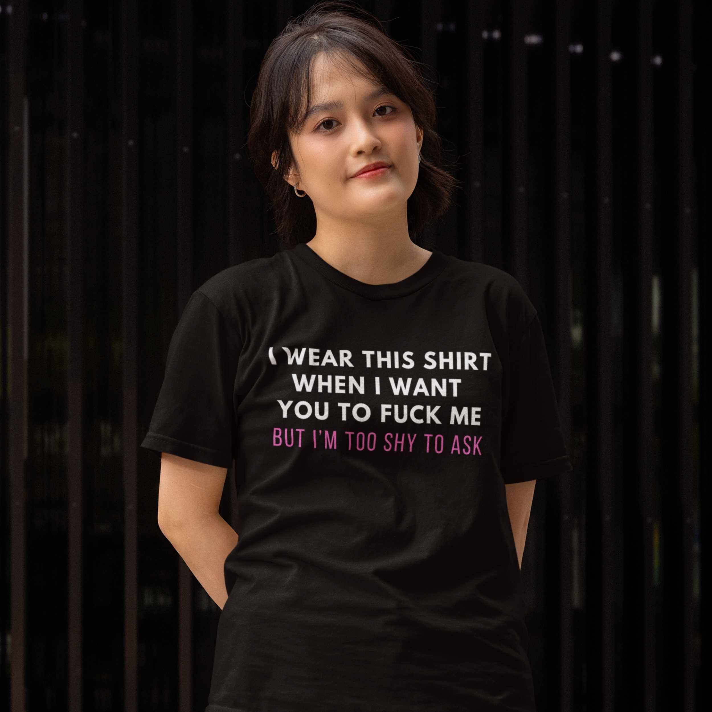 Person wearing a black t-shirt with a provocative message against a dark background