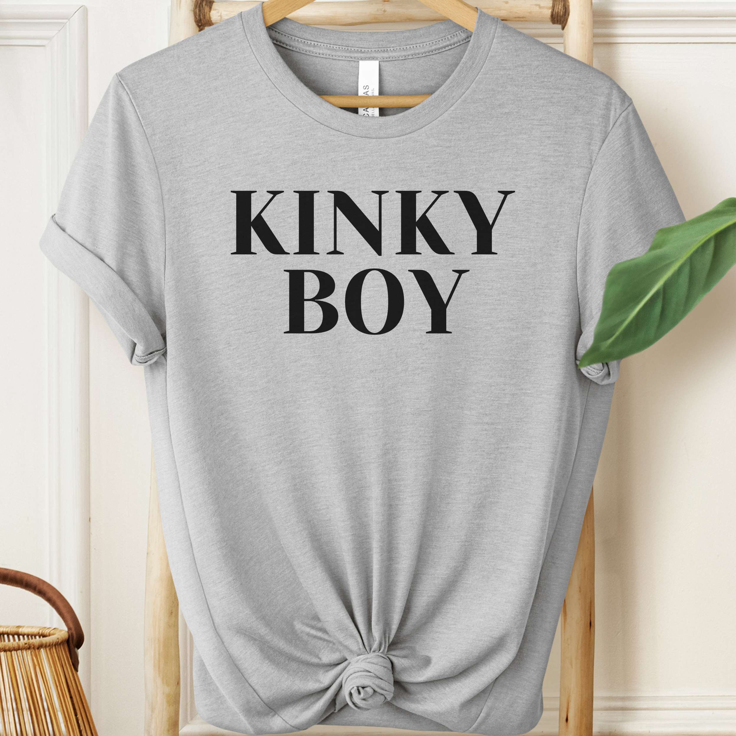 Gray t-shirt with 'KINKY BOY' text on a hanger against a neutral background