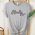 Gray t-shirt with 'Kinky' text on a hanger against a neutral background