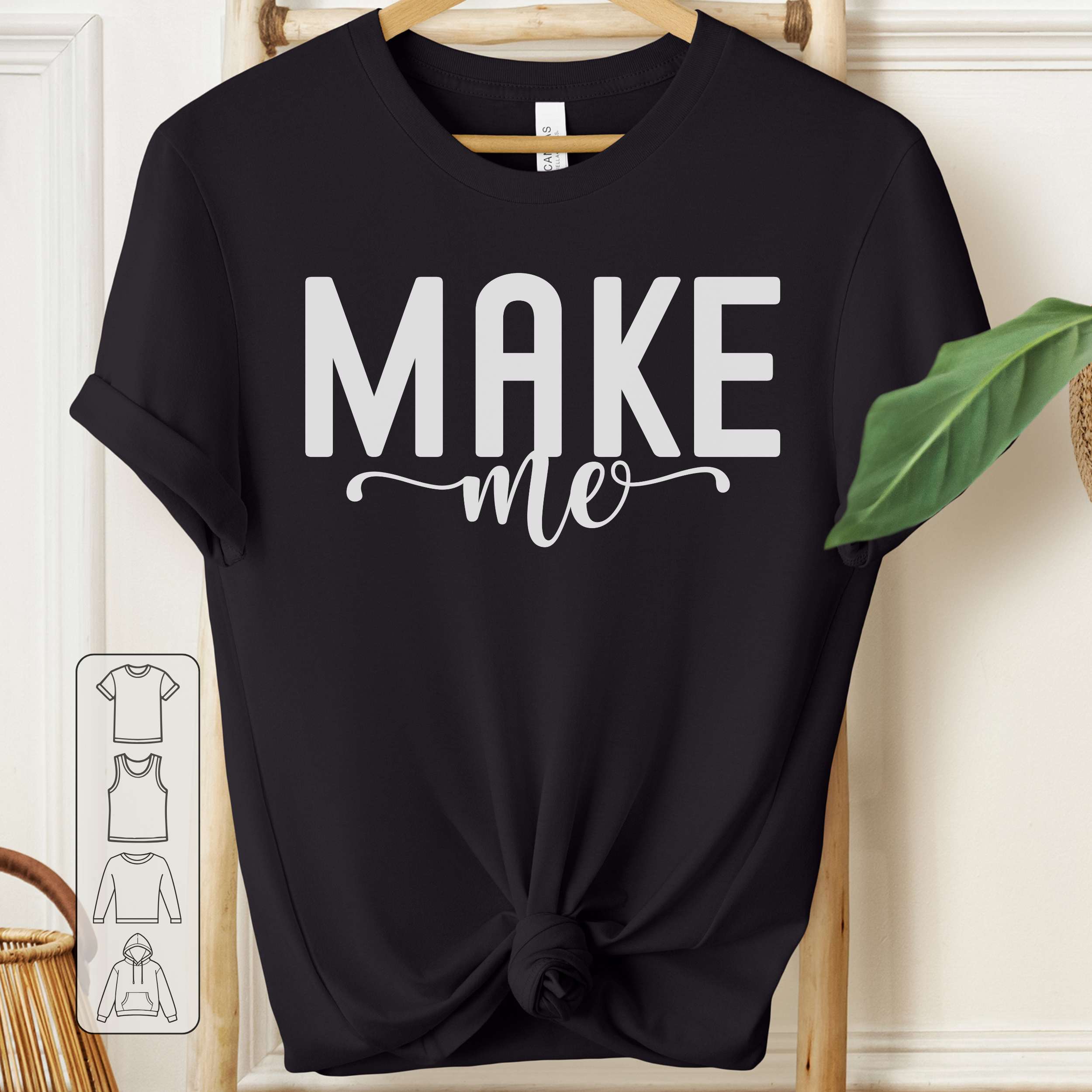 Black t-shirt with 'MAKE me' text on a wooden hanger.