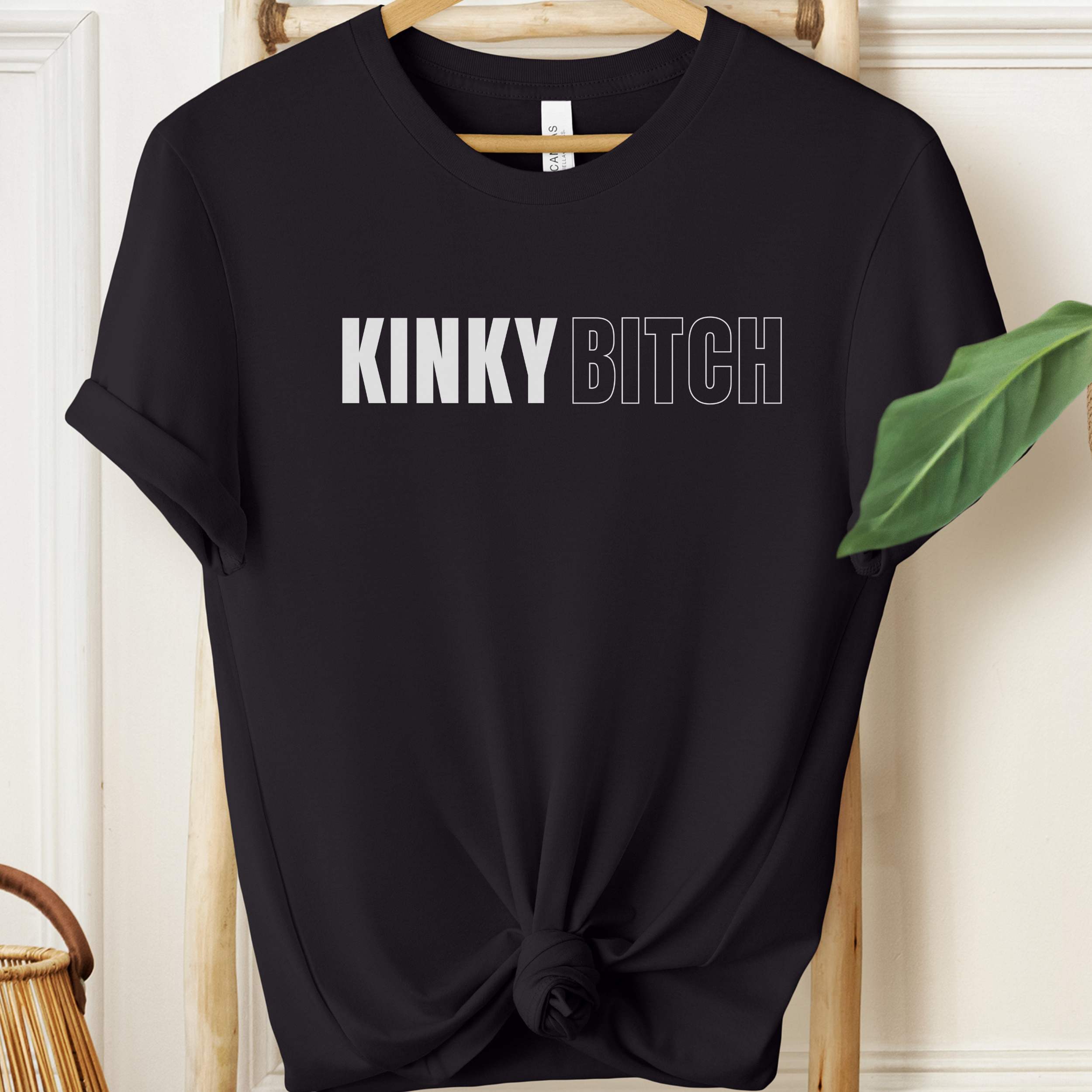 Black t-shirt with 'KINKY BITCH' text on a hanger.