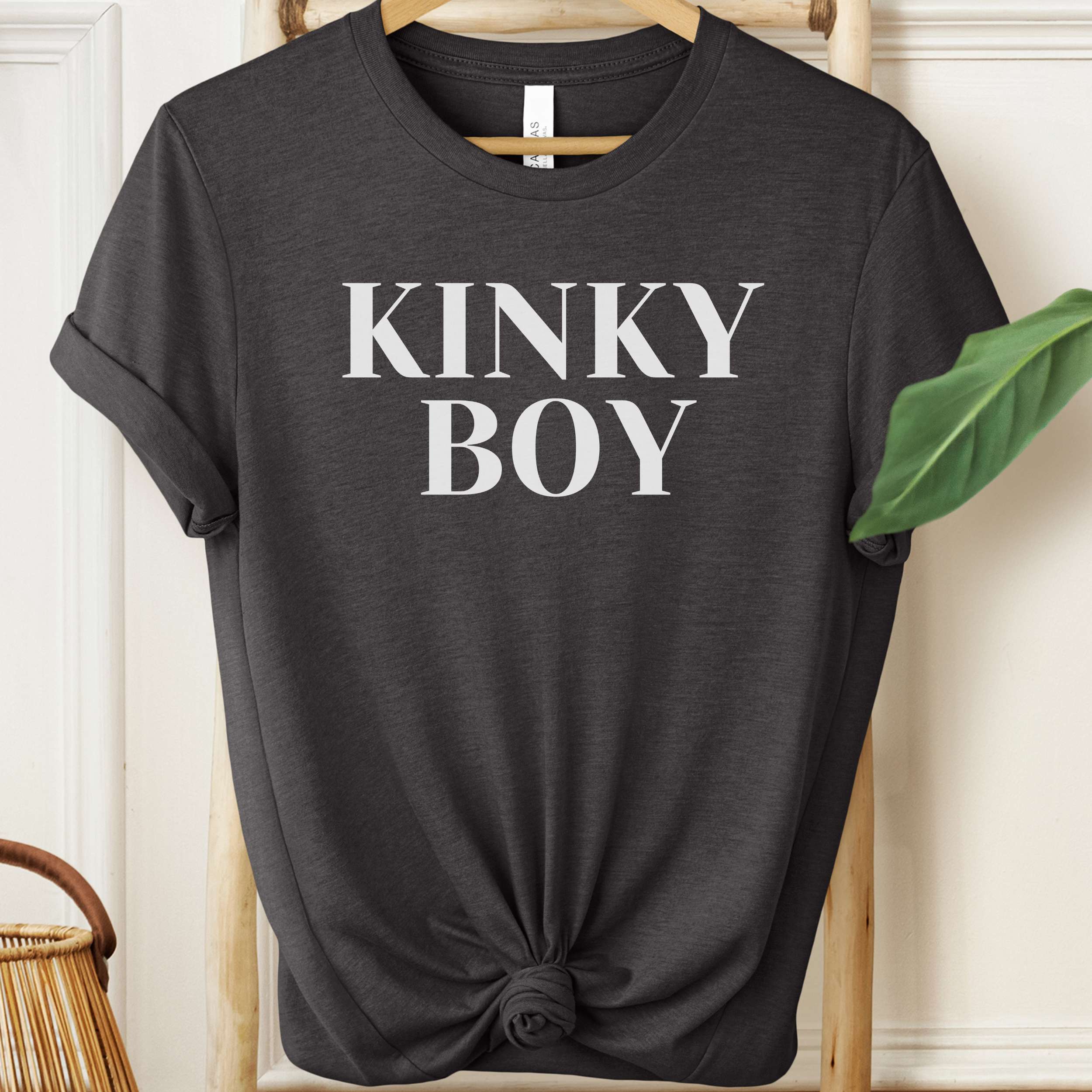 Black t-shirt with 'KINKY BOY' text on a hanger against a neutral background