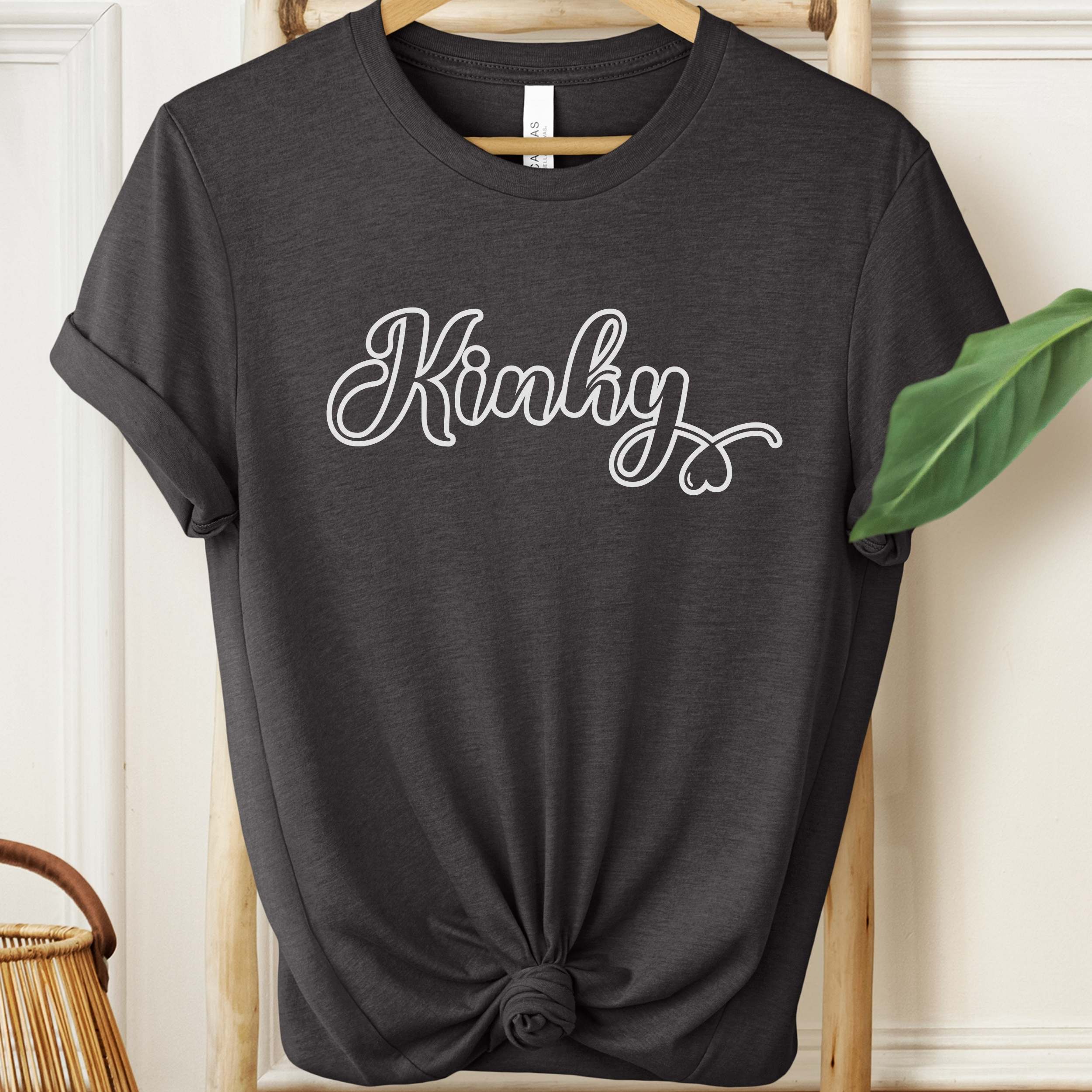 Black t-shirt with 'Kinky' text on a hanger against a neutral background