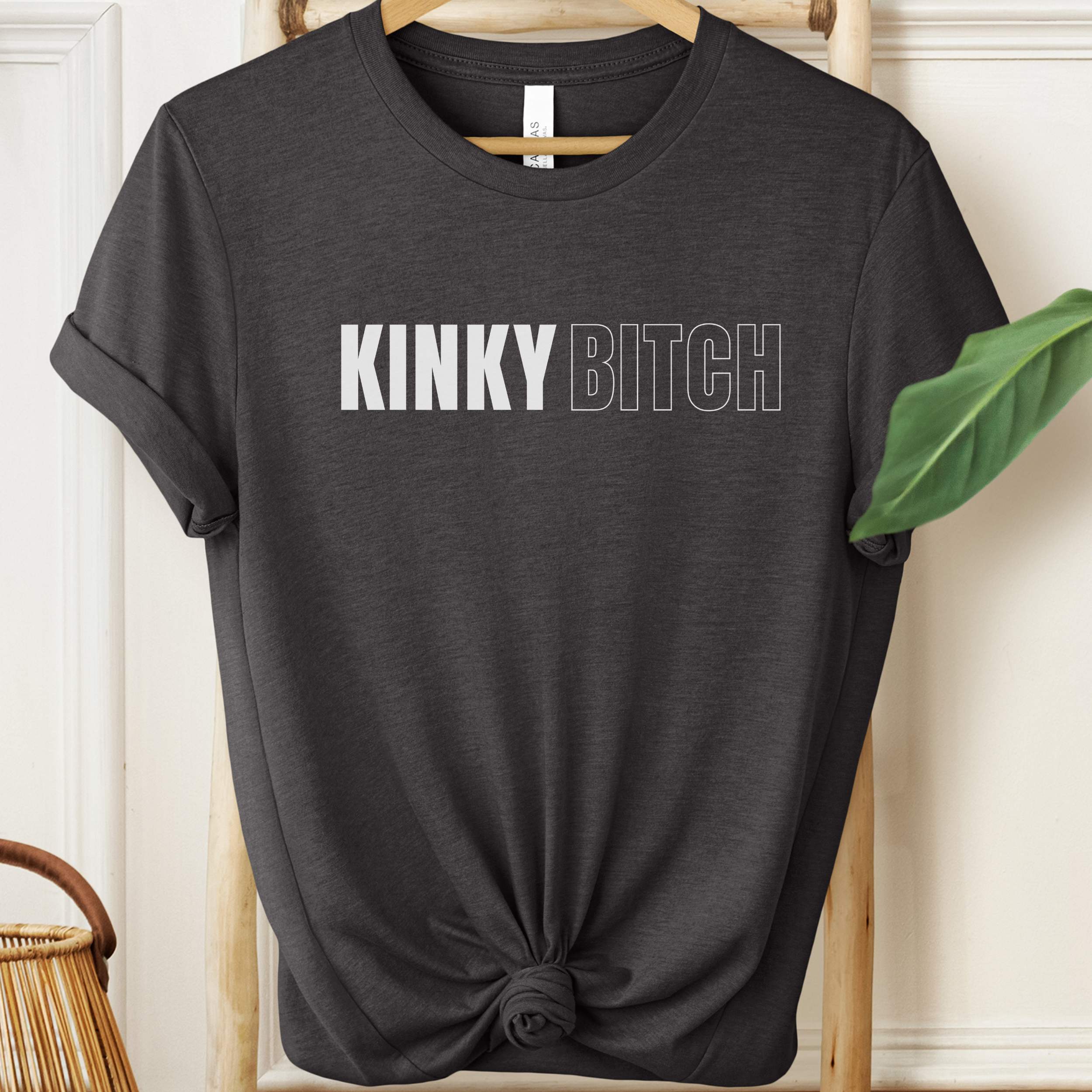 Black t-shirt with 'KINKY BITCH' text on a hanger.