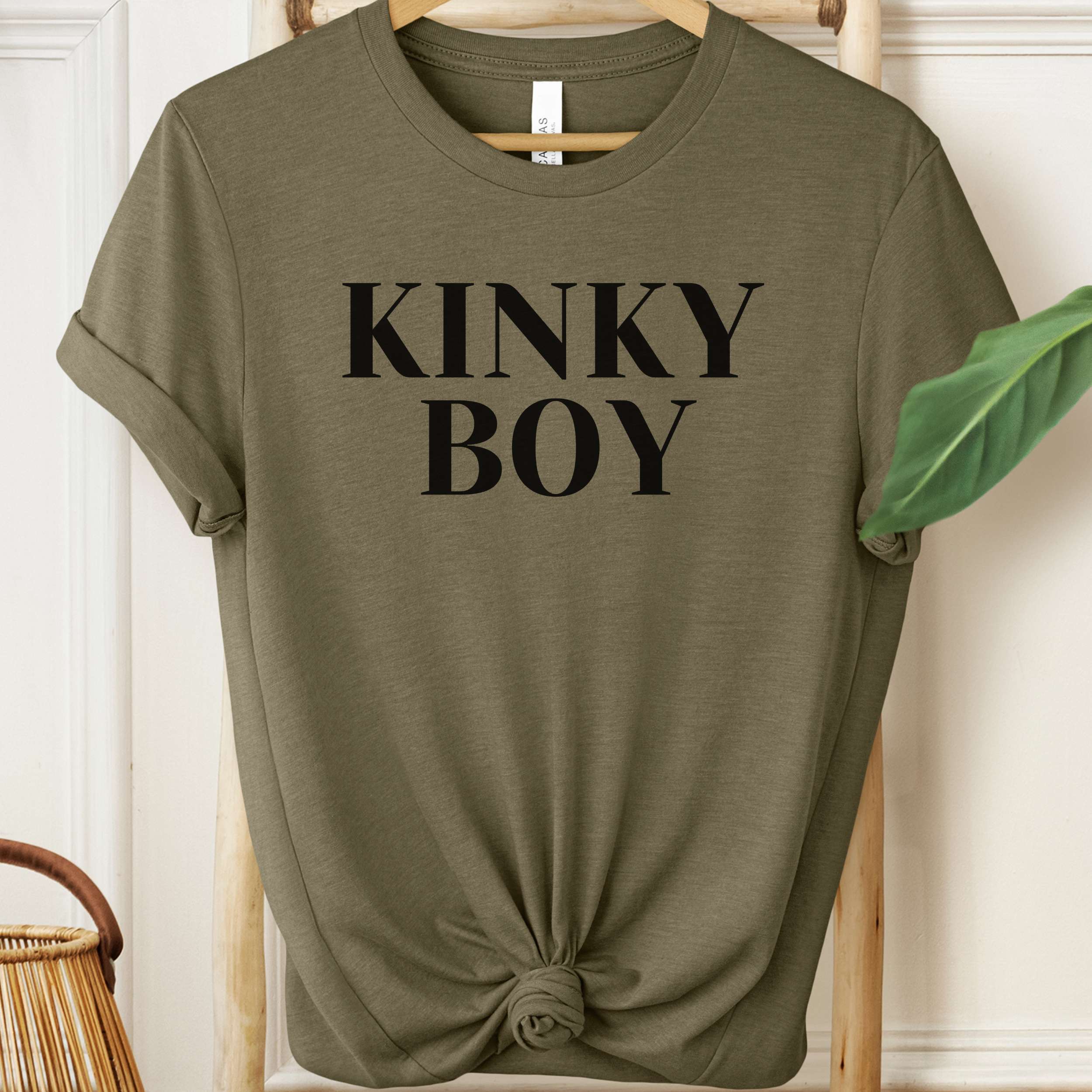 Olive green t-shirt with 'KINKY BOY' text on a hanger.
