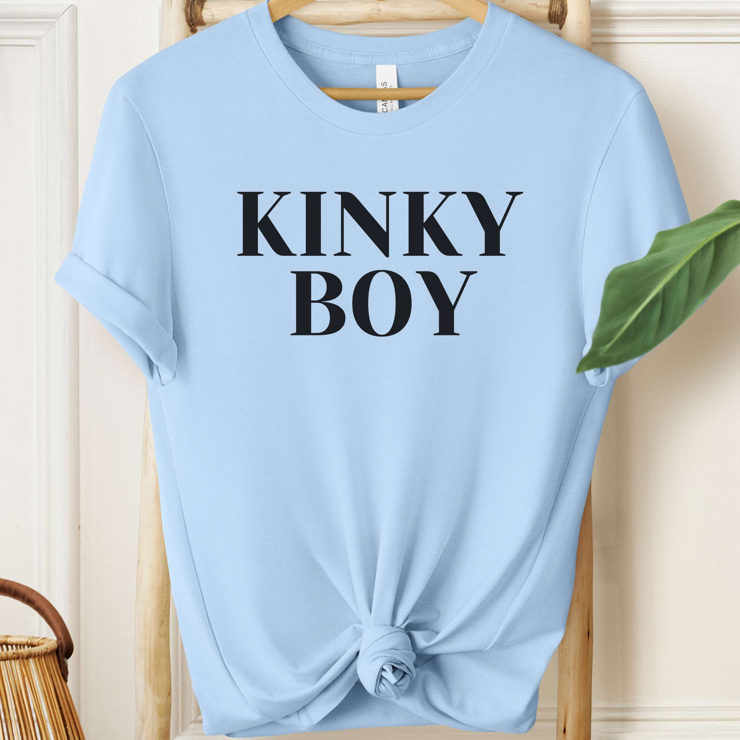 Light blue t-shirt with 'KINKY BOY' text on a wooden hanger.