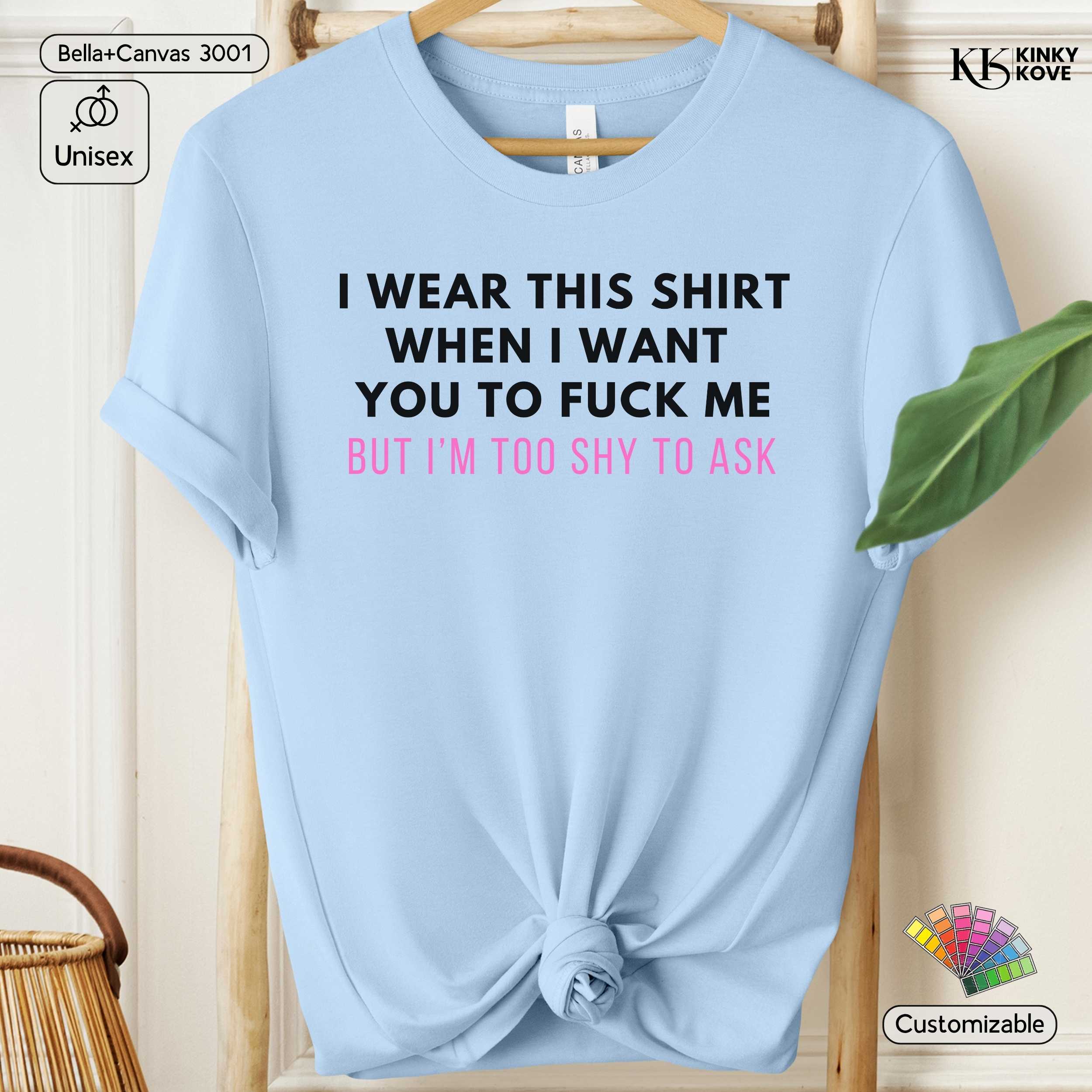 Light blue t-shirt with black and pink text on a wooden hanger.