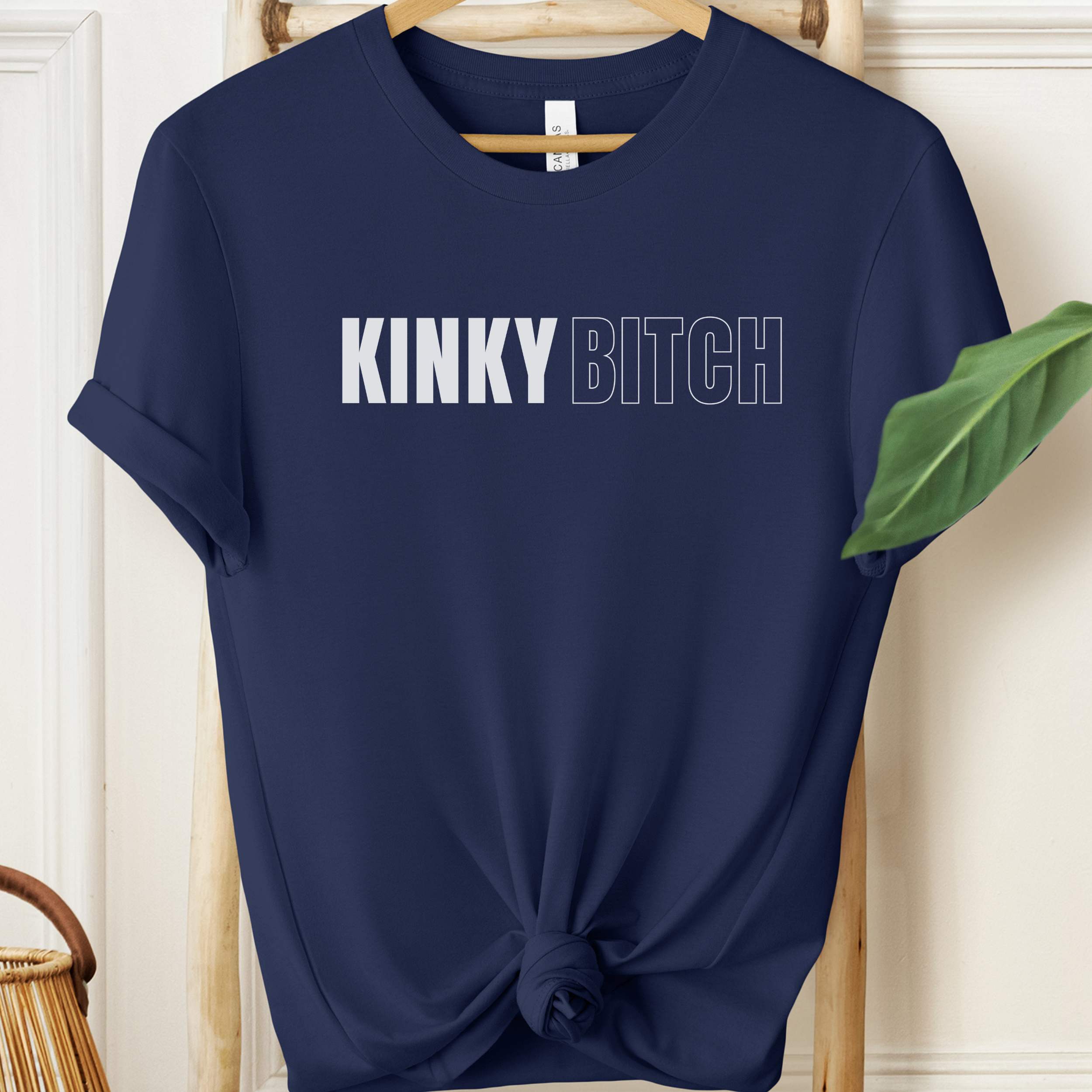 Navy blue t-shirt with 'KINKY BITCH' text on a hanger.