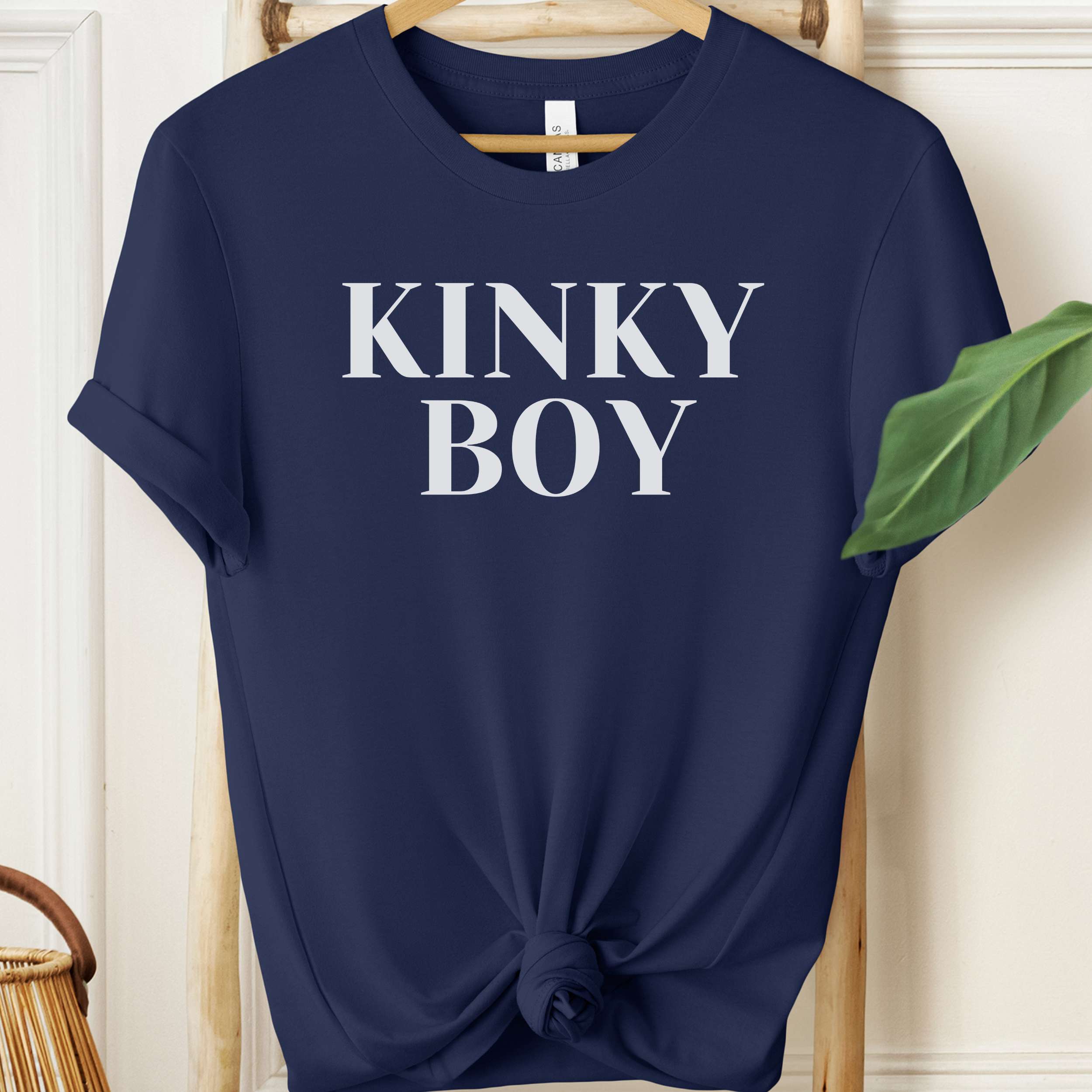 Navy blue t-shirt with 'KINKY BOY' text on a wooden hanger.