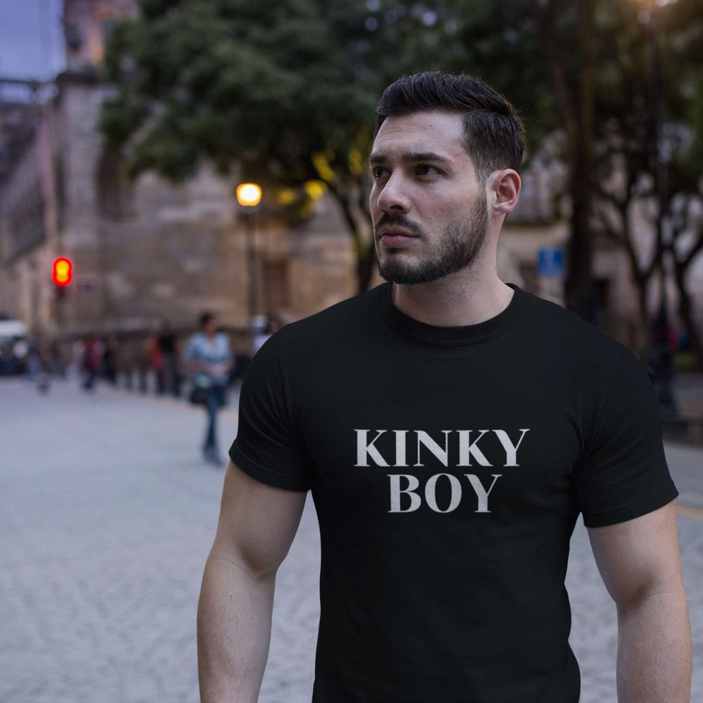 Man wearing a black t-shirt with 'KINKY BOY' text on a city street.