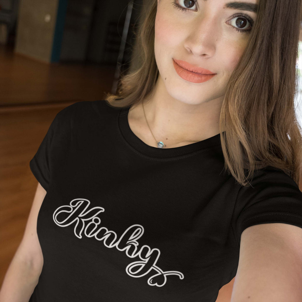 Person wearing a black t-shirt with 'Kinky' printed on it, indoors.