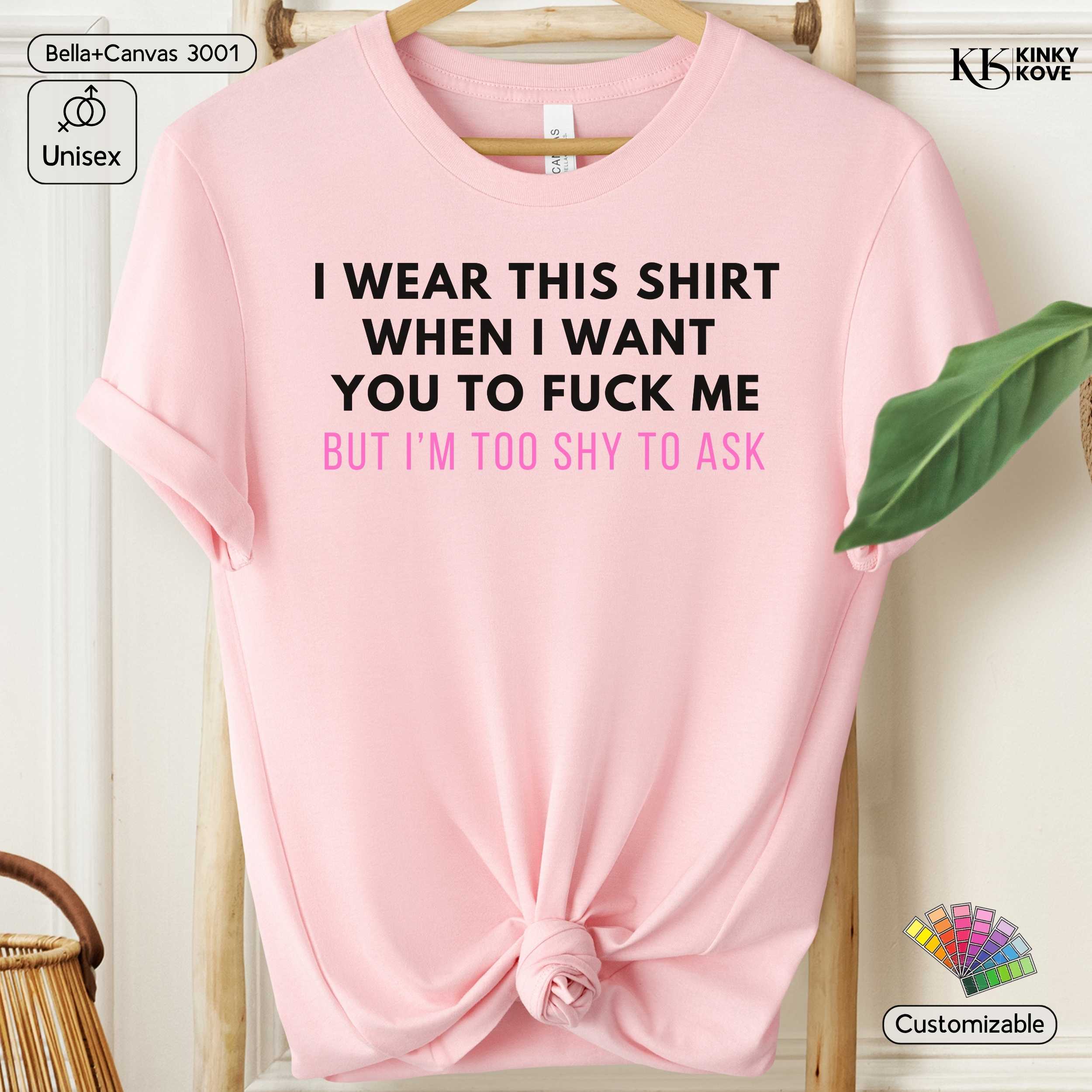Pink t-shirt with text on a hanger against a neutral background