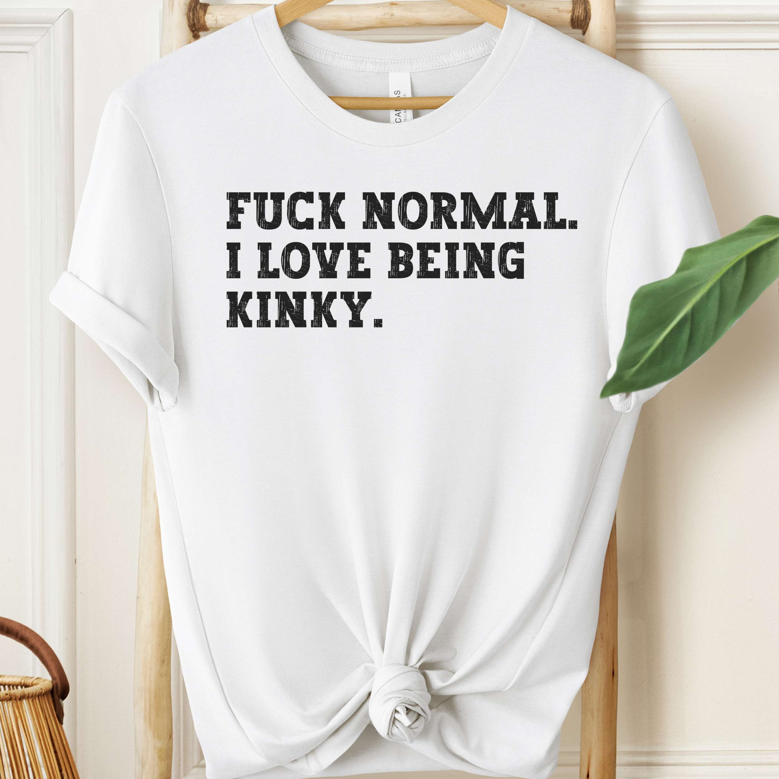 White t-shirt with black text on a hanger against a neutral background