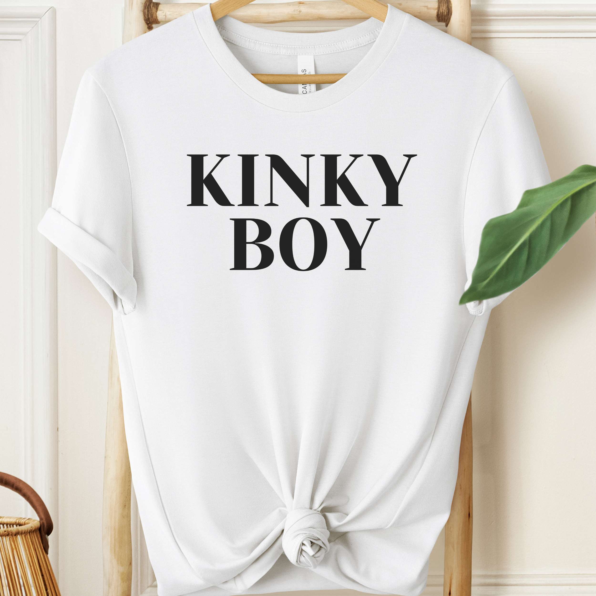 White t-shirt with 'KINKY BOY' text on a hanger against a neutral background
