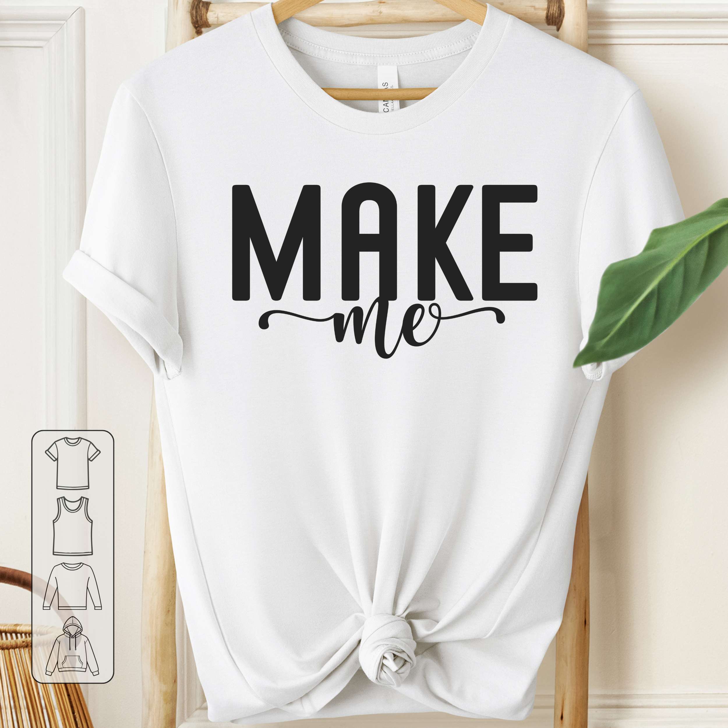White t-shirt with 'MAKE me' text on a wooden hanger against a white background
