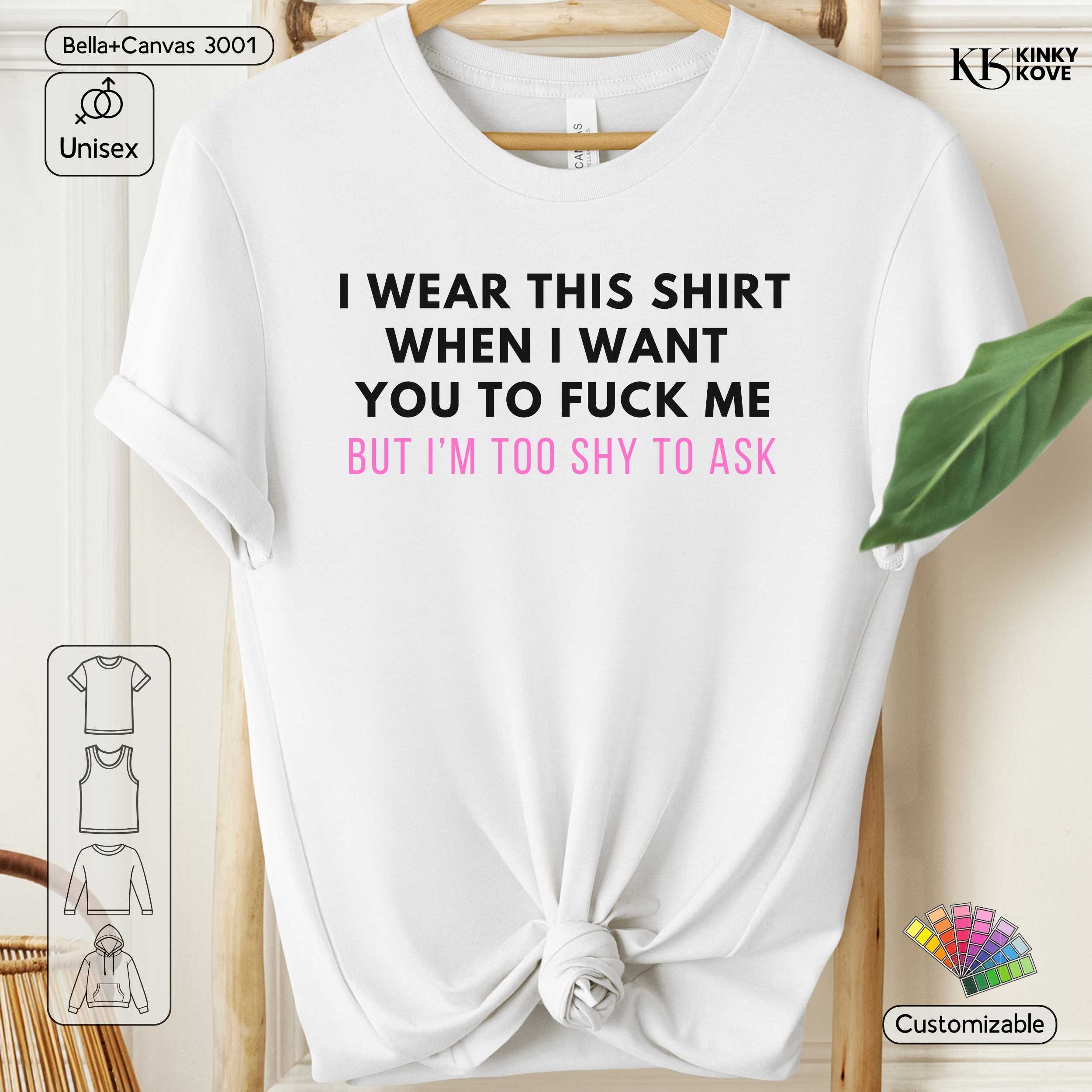 White t-shirt with black and pink text on a wooden hanger