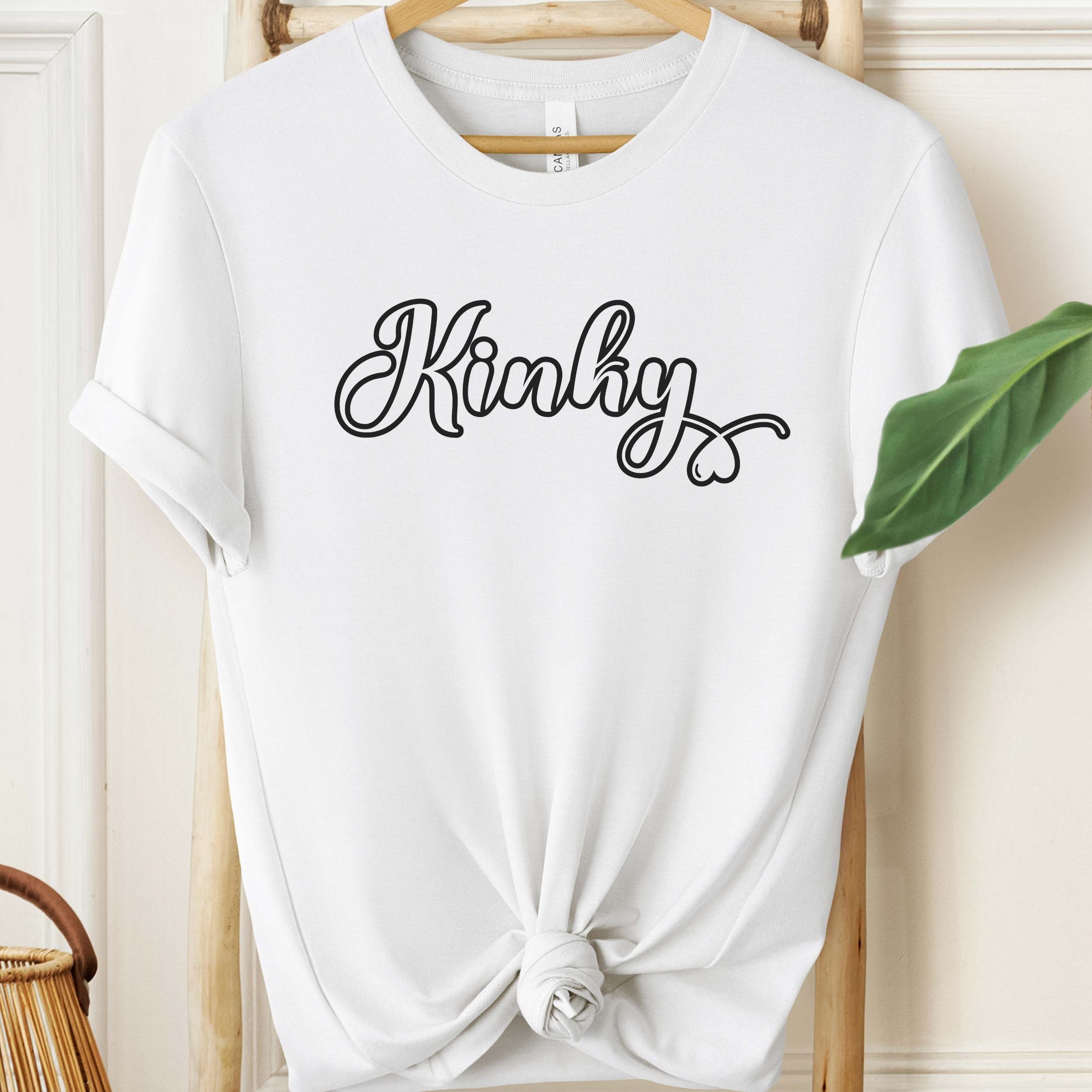 White t-shirt with 'Kinky' text on a hanger against a neutral background