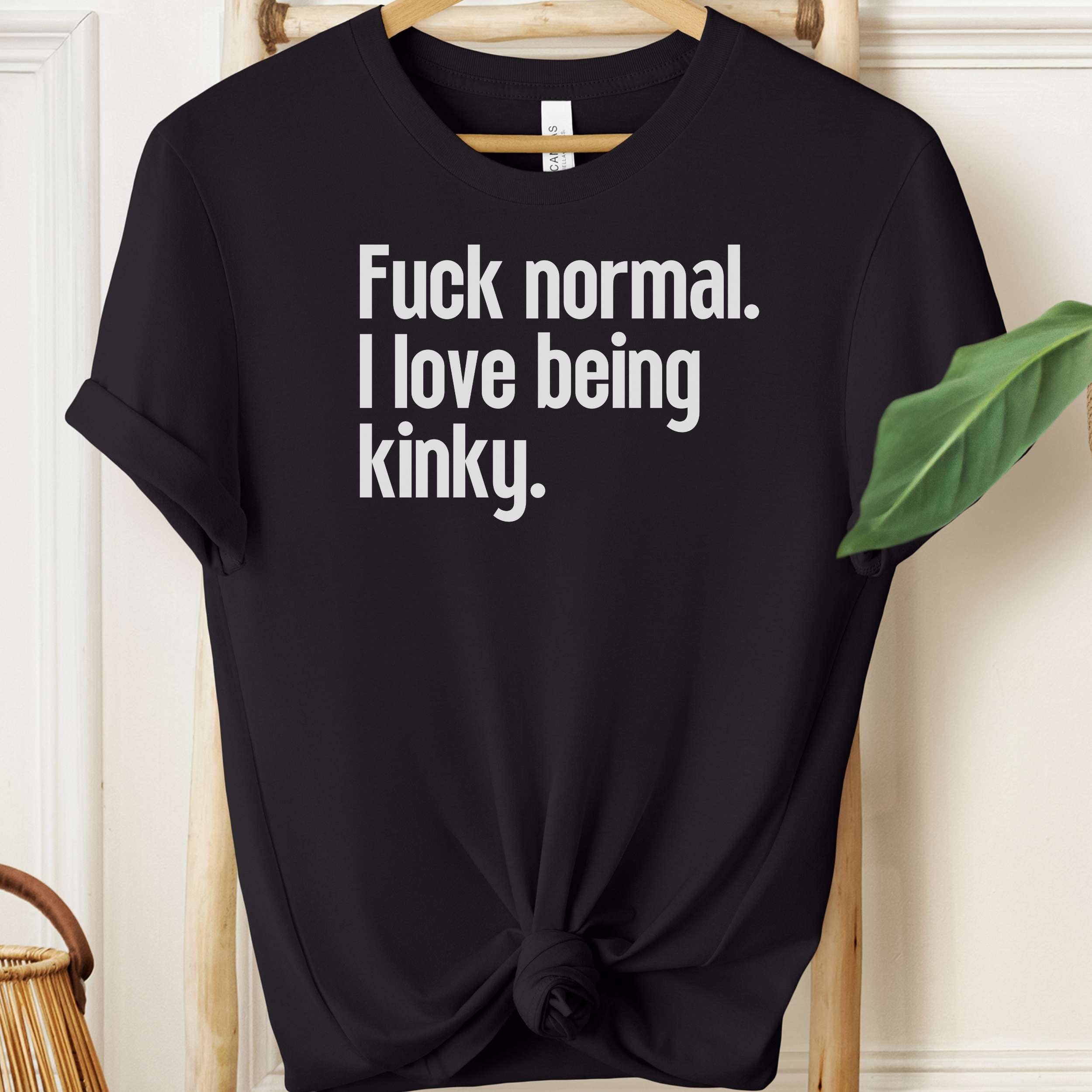 Black t-shirt with white text on a hanger against a neutral background