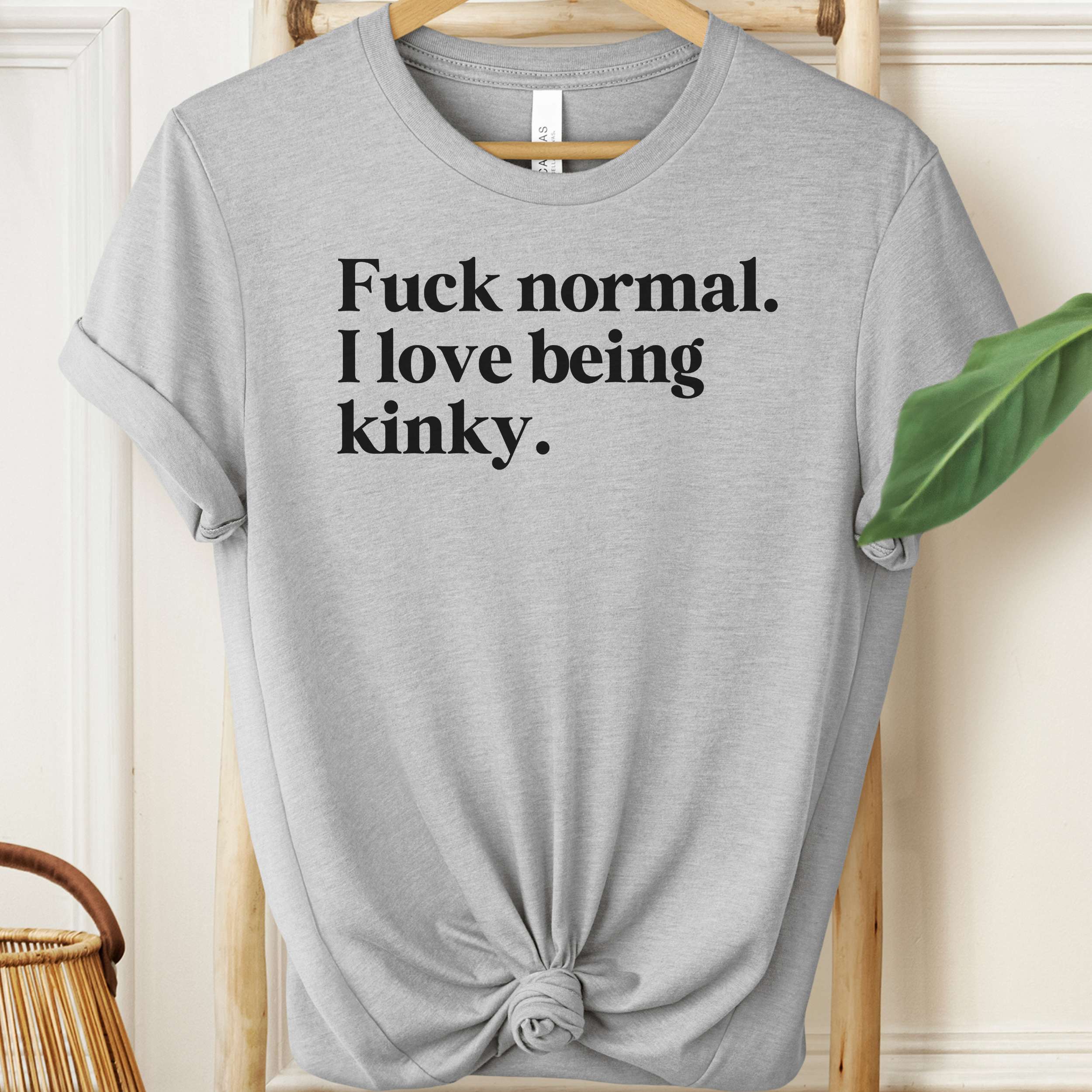 Gray t-shirt with black text on a hanger against a neutral background