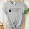 Gray t-shirt with '#KINKY' text on a hanger against a neutral background