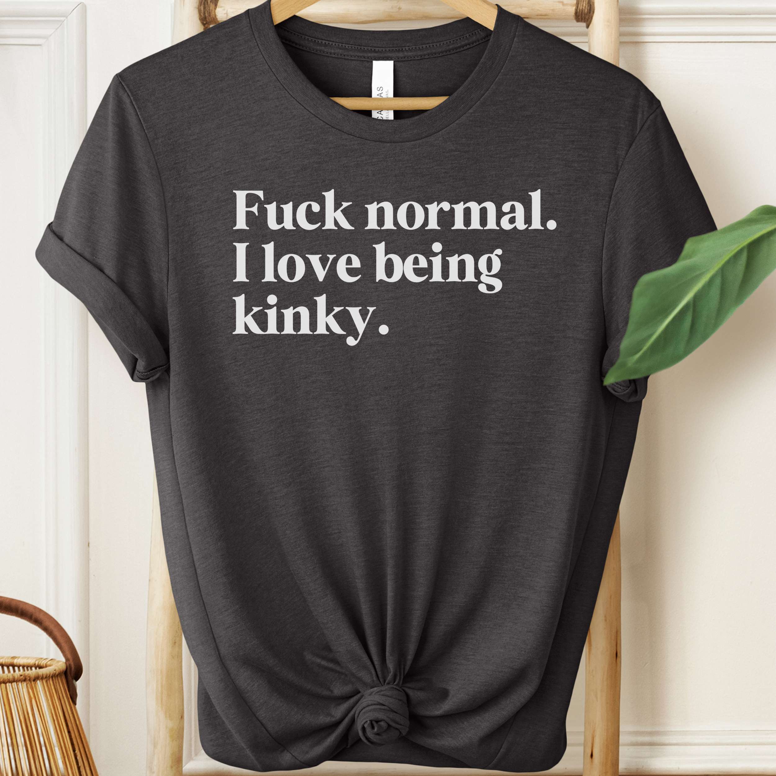 Black t-shirt with white text on a hanger against a neutral background