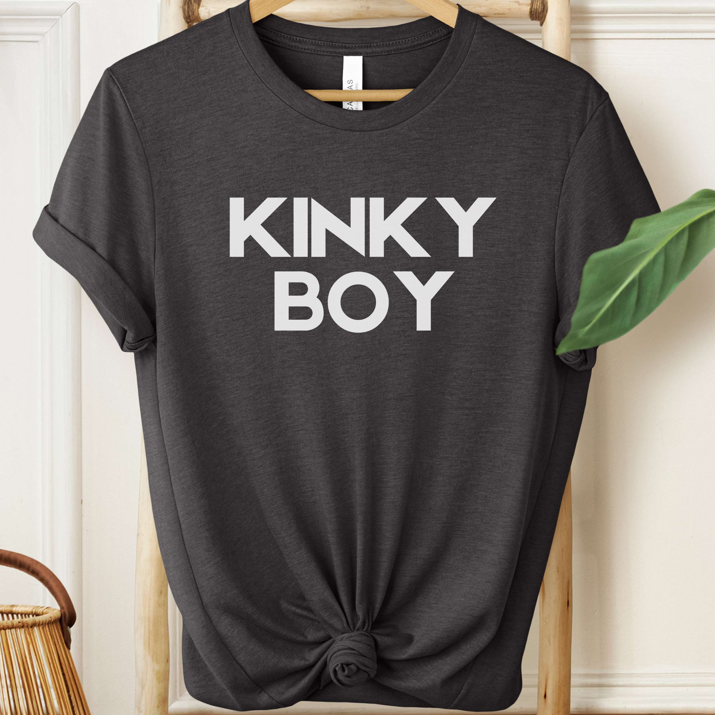 Black t-shirt with 'KINKY BOY' text on a hanger against a neutral background