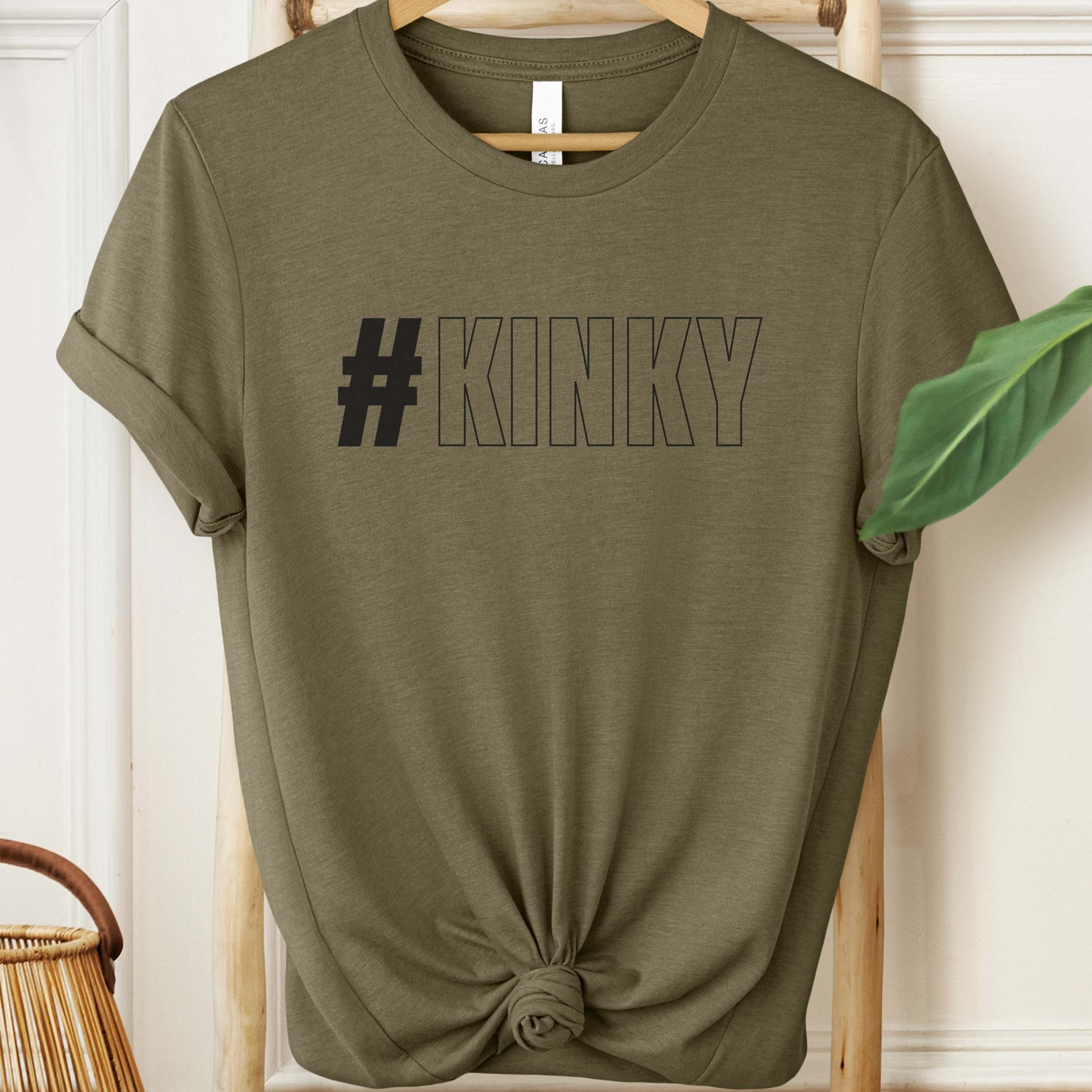 Olive green t-shirt with '#KINKY' text on a wooden hanger.