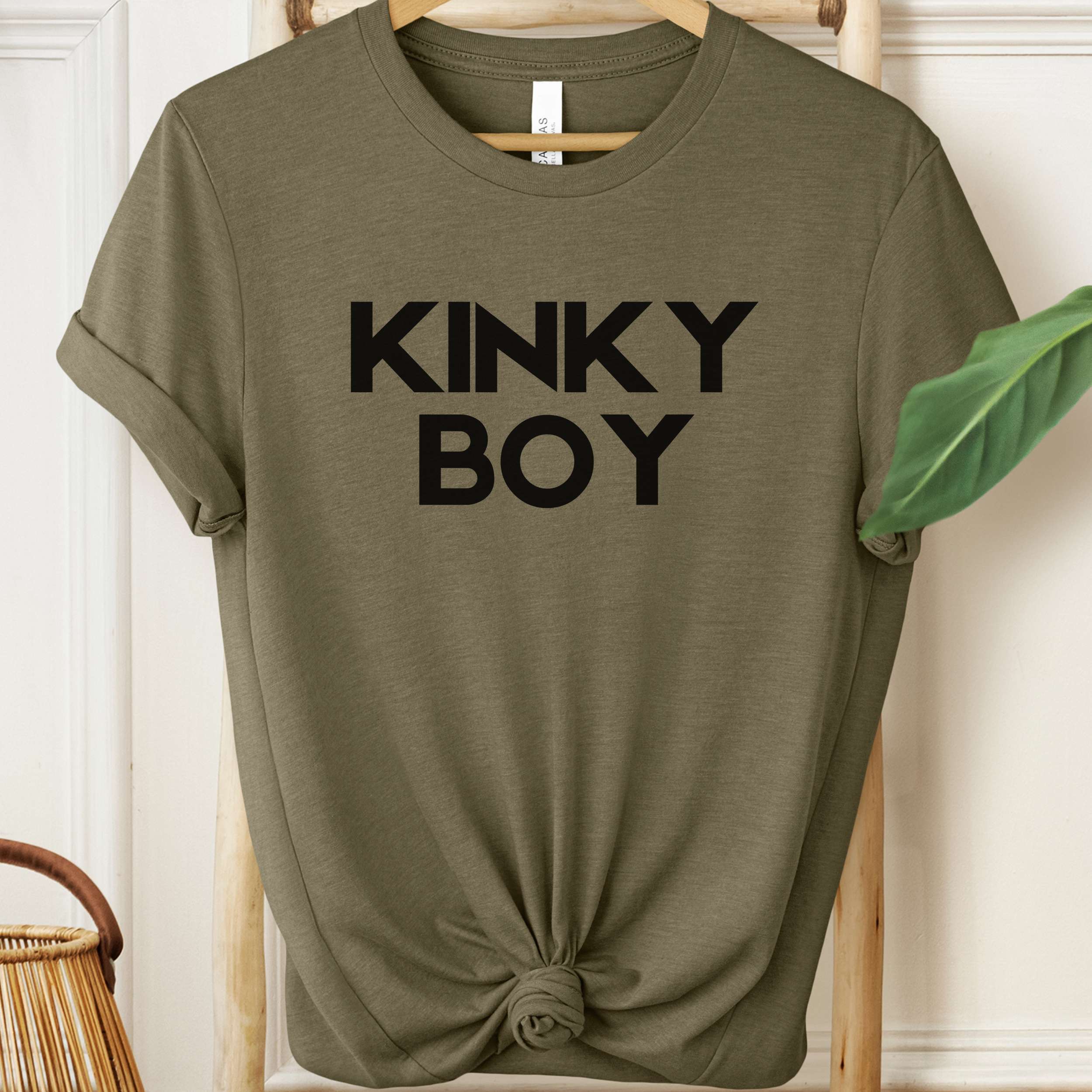 Olive green t-shirt with 'KINKY BOY' text on a hanger.