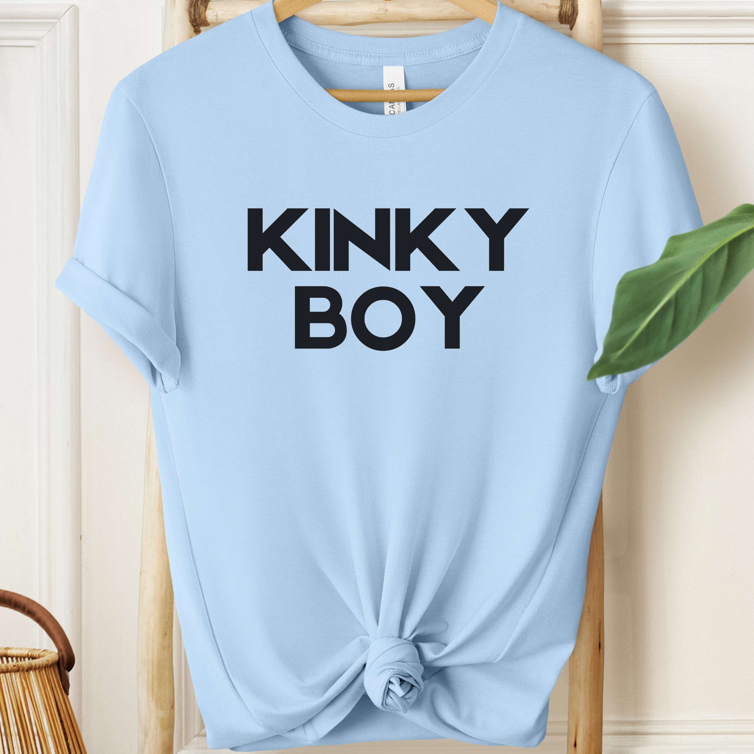 Light blue t-shirt with 'KINKY BOY' text on a wooden hanger.