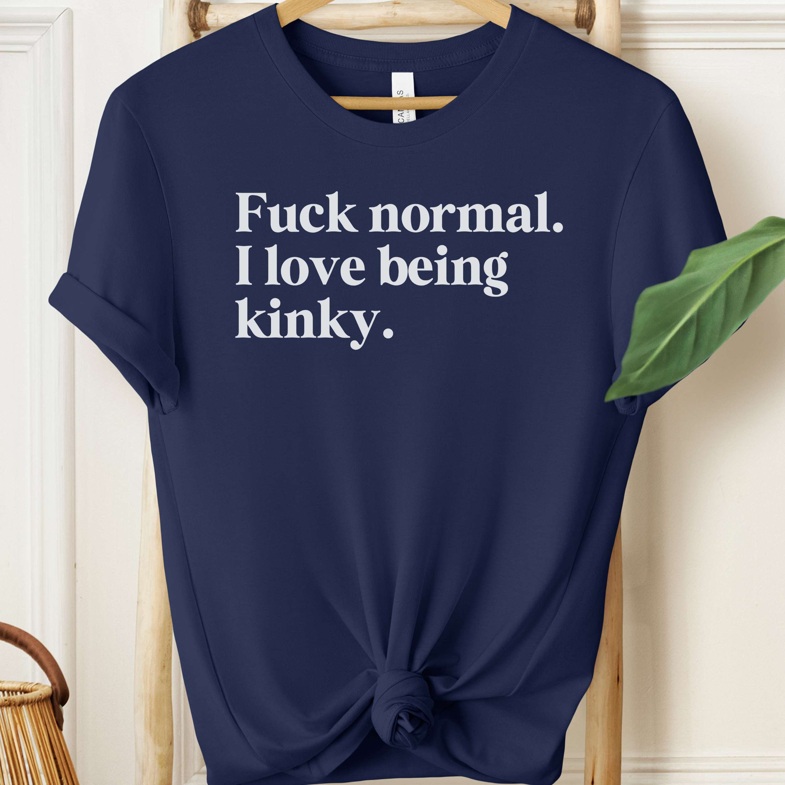 Navy blue t-shirt with white text on a hanger against a neutral background