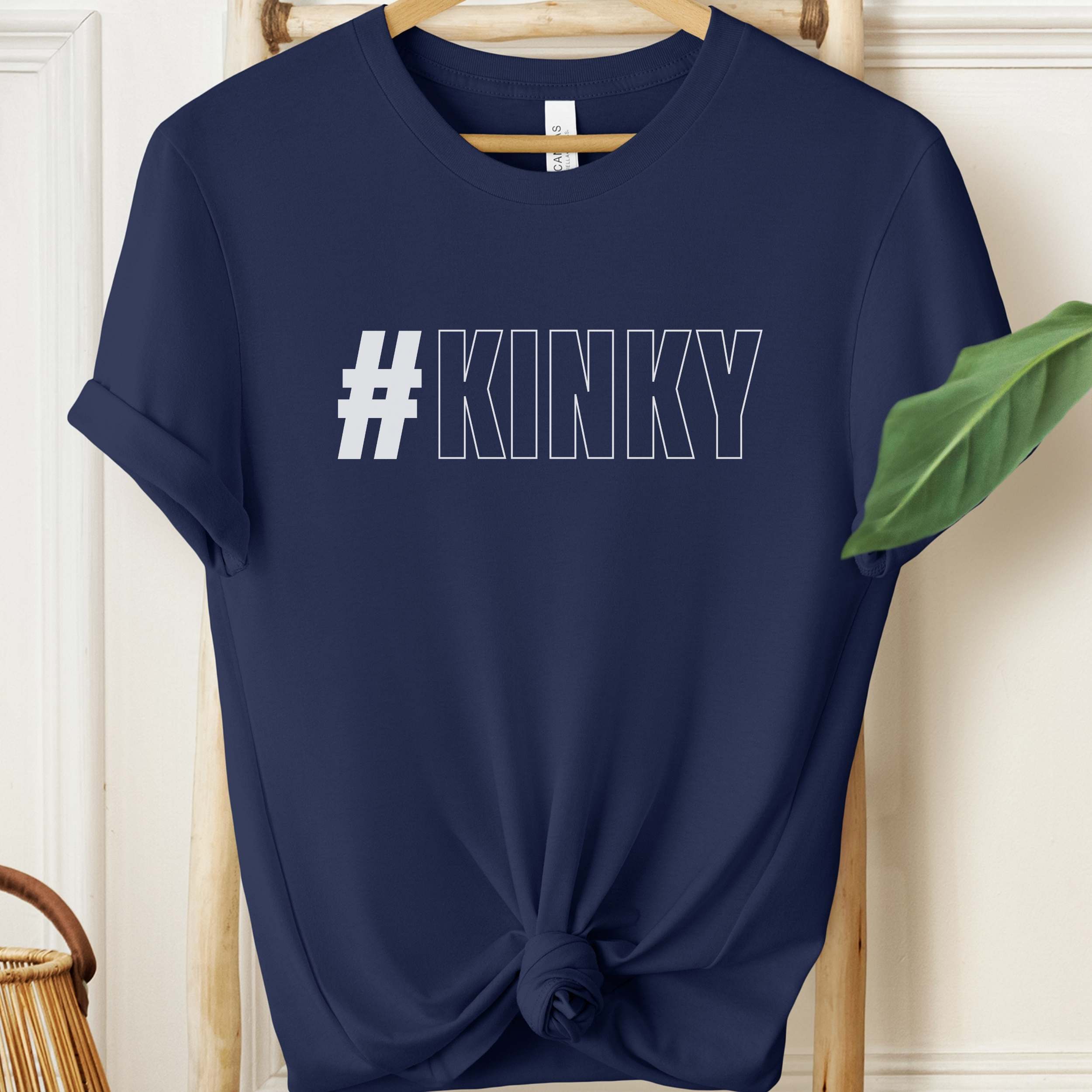 Navy blue t-shirt with '#KINKY' text on a wooden hanger.