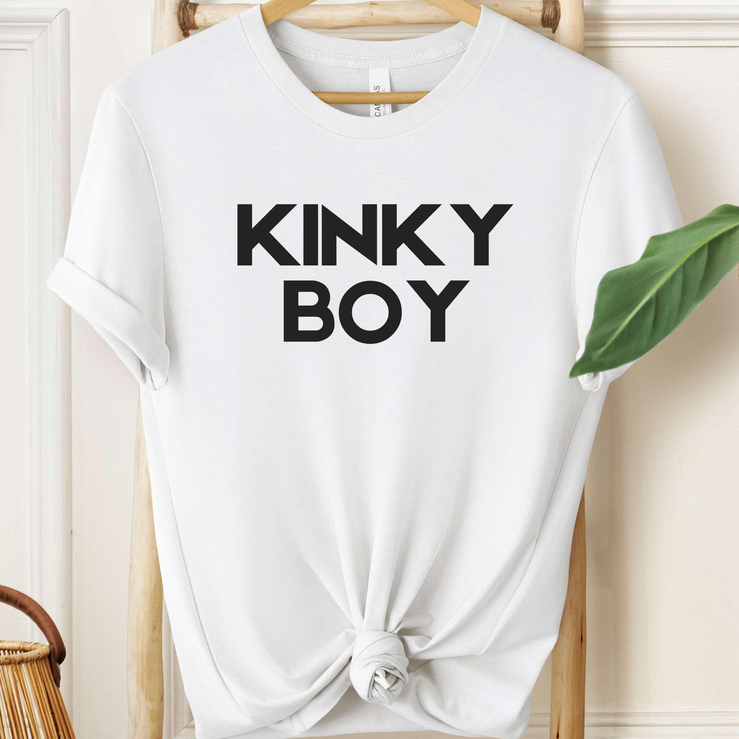 White t-shirt with 'KINKY BOY' text on a hanger against a neutral background