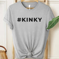 Gray t-shirt with '#KINKY' text on a hanger against a neutral background