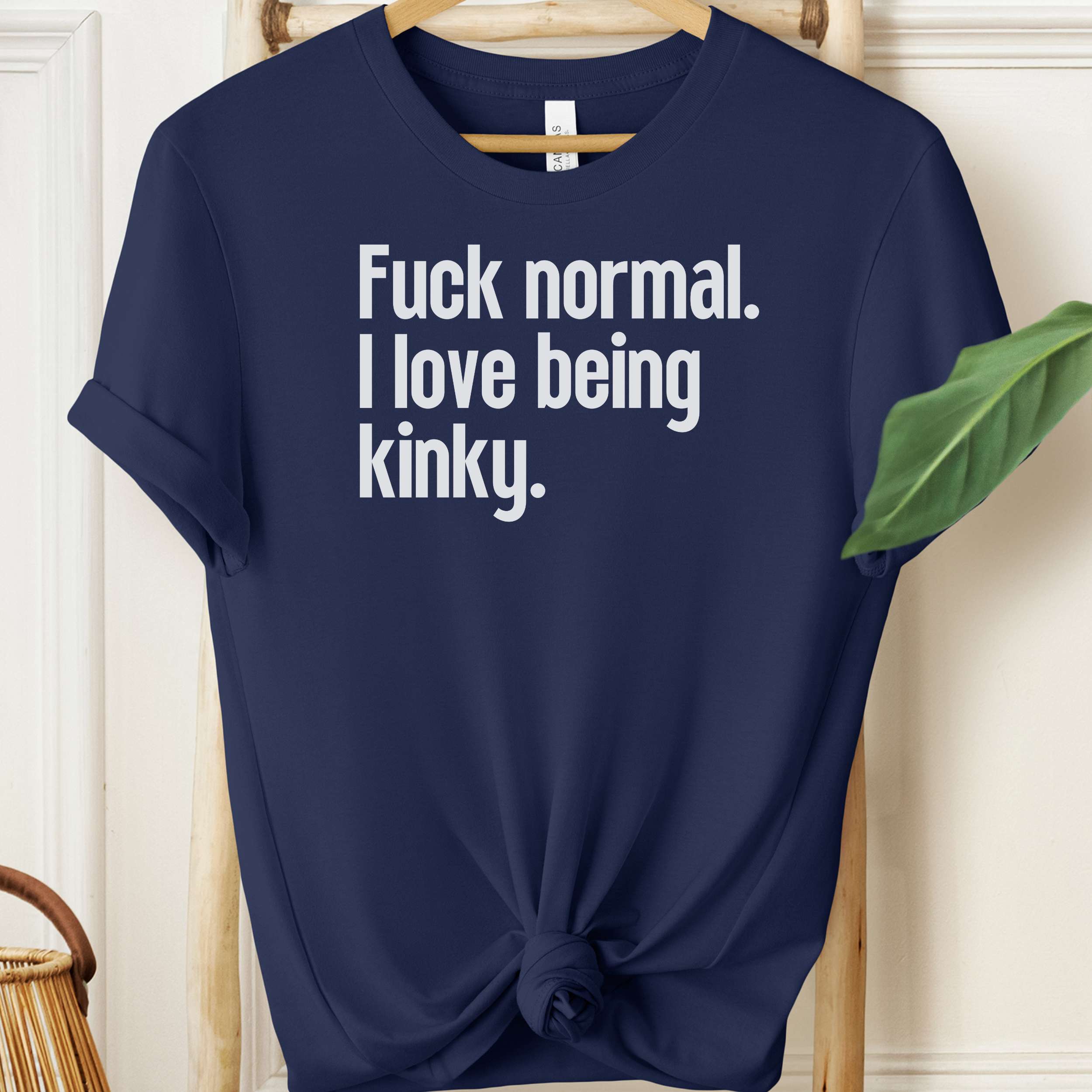 Navy blue t-shirt with white text on a hanger against a neutral background