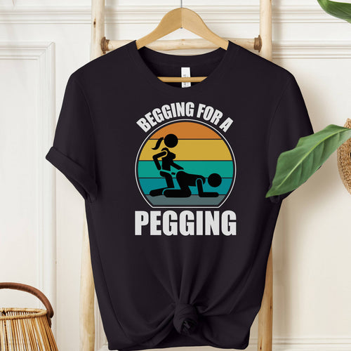 Black t-shirt with graphic design and text on a hanger against a white wall.