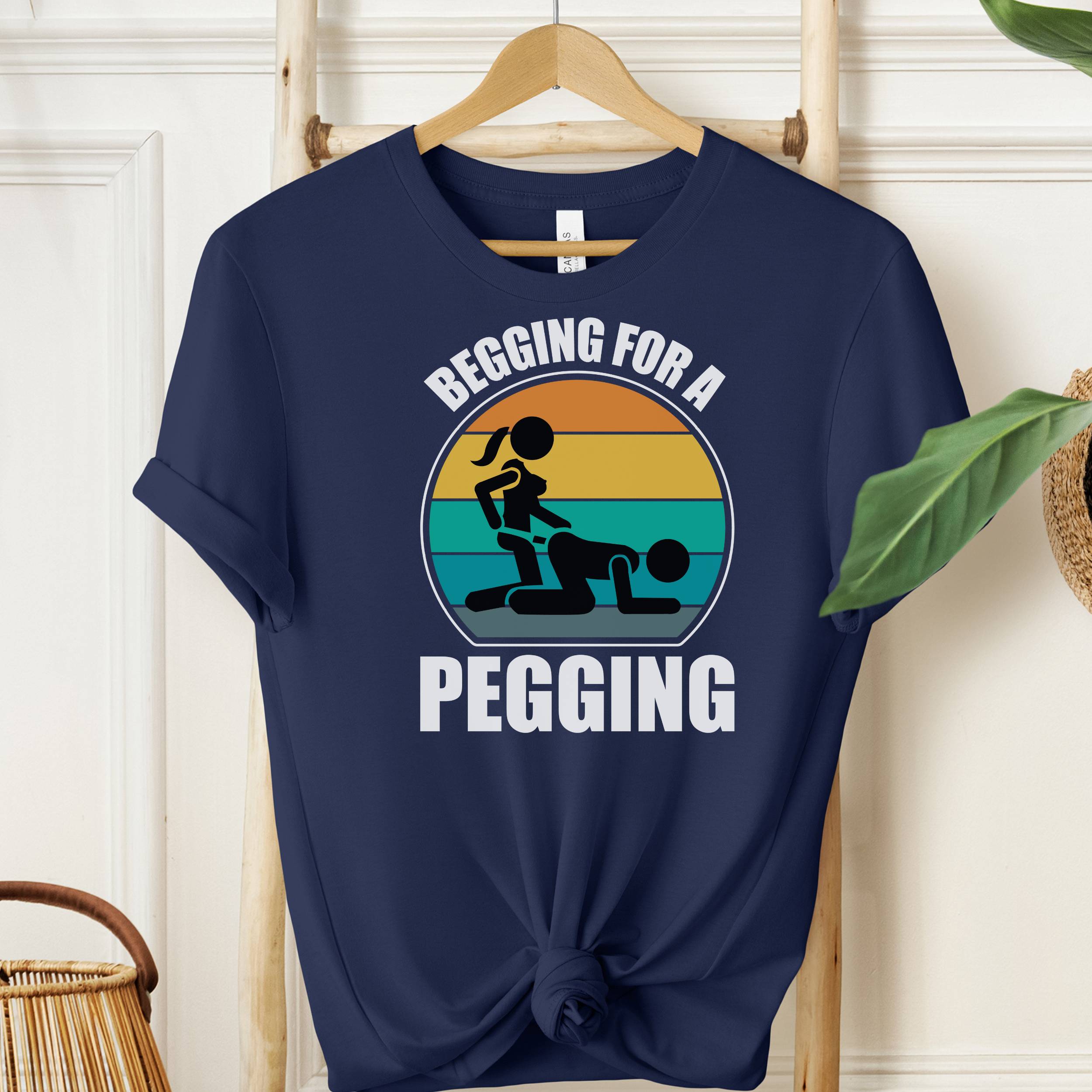 Navy blue t-shirt with graphic design and text on a wooden hanger against a white wall.