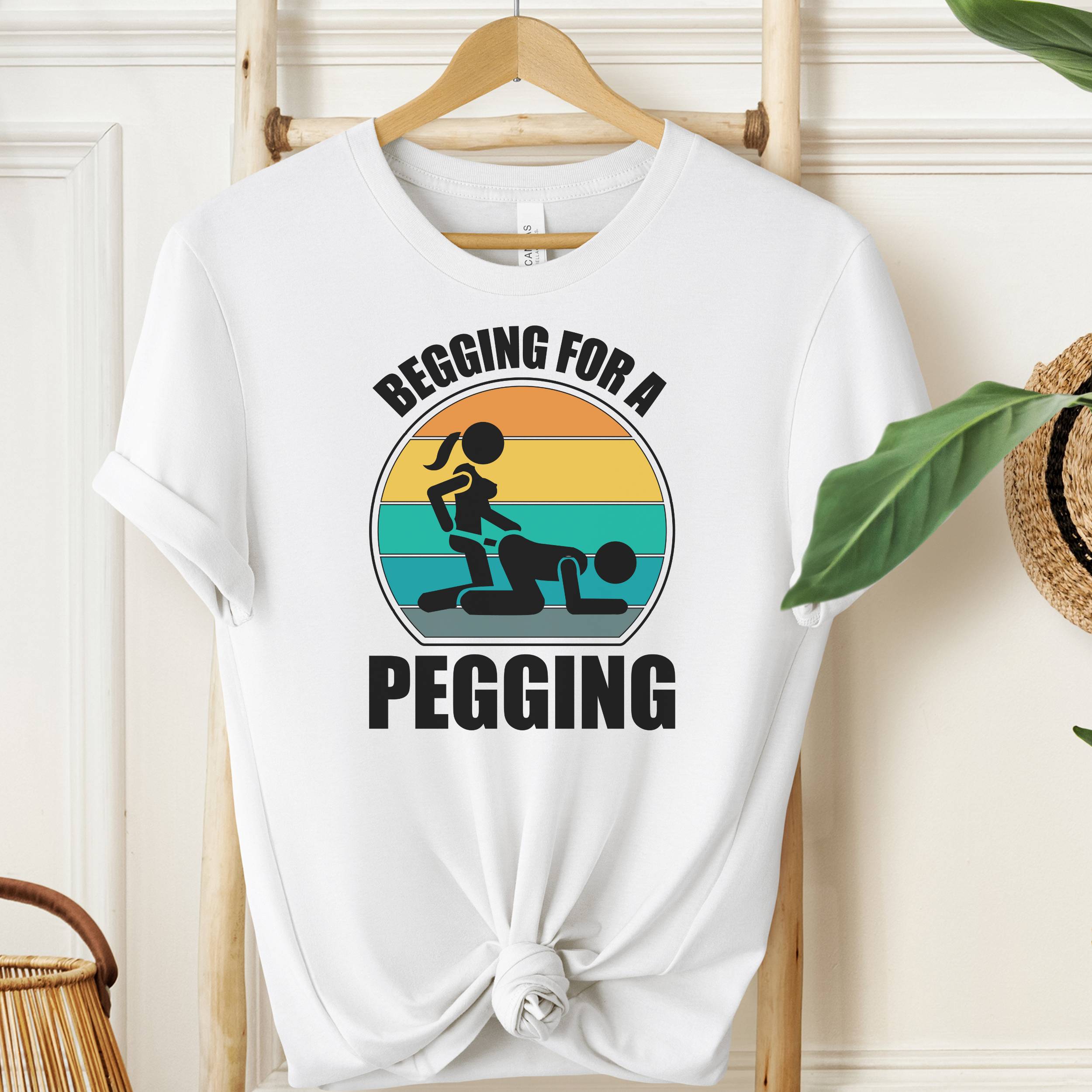 White t-shirt with graphic design and text on a hanger against a neutral background