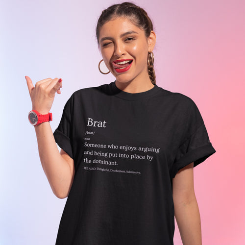 Woman wearing a black t-shirt with a definition of 'brat' and posing against a gradient background.