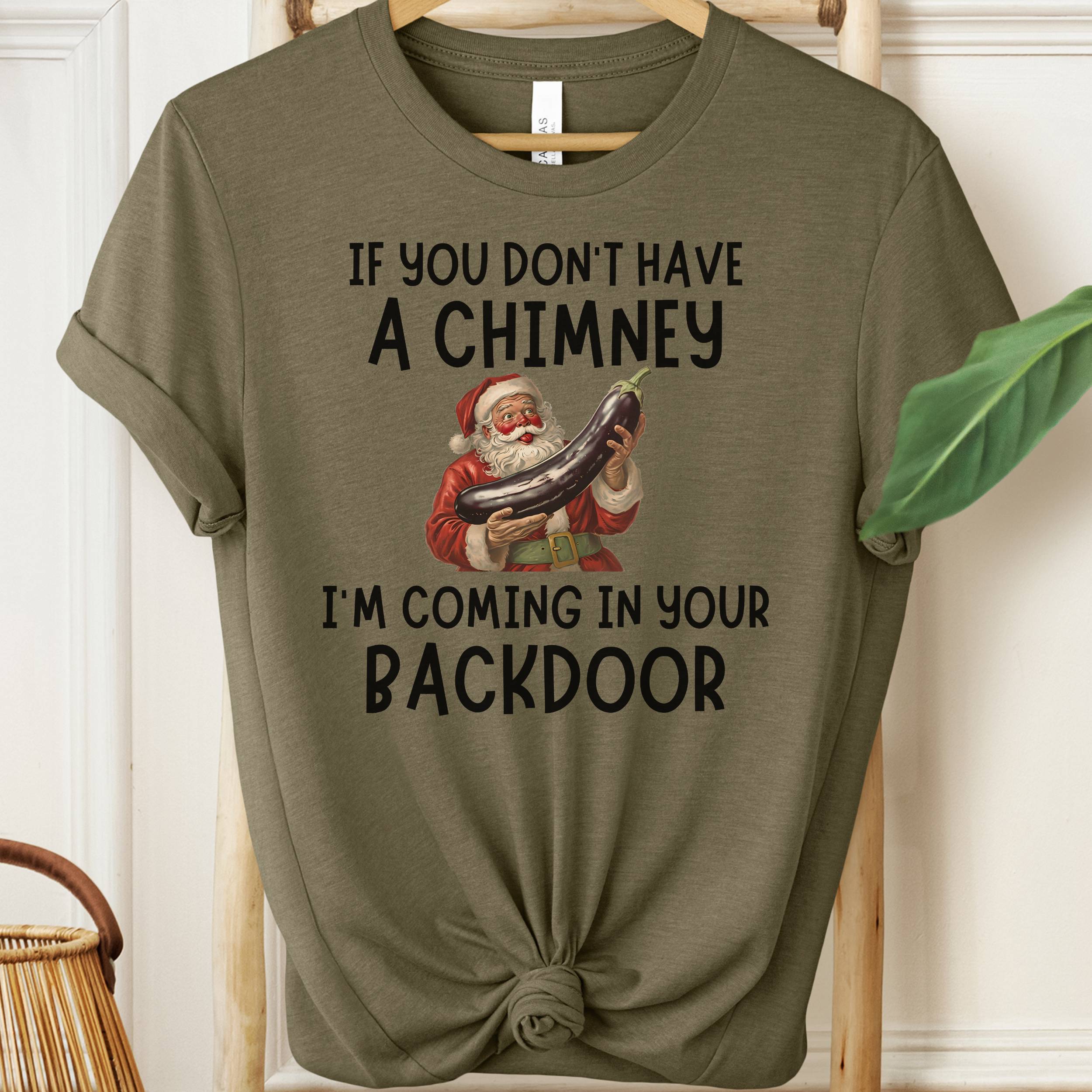 Olive green t-shirt with Santa Claus graphic and humorous text on a hanger.