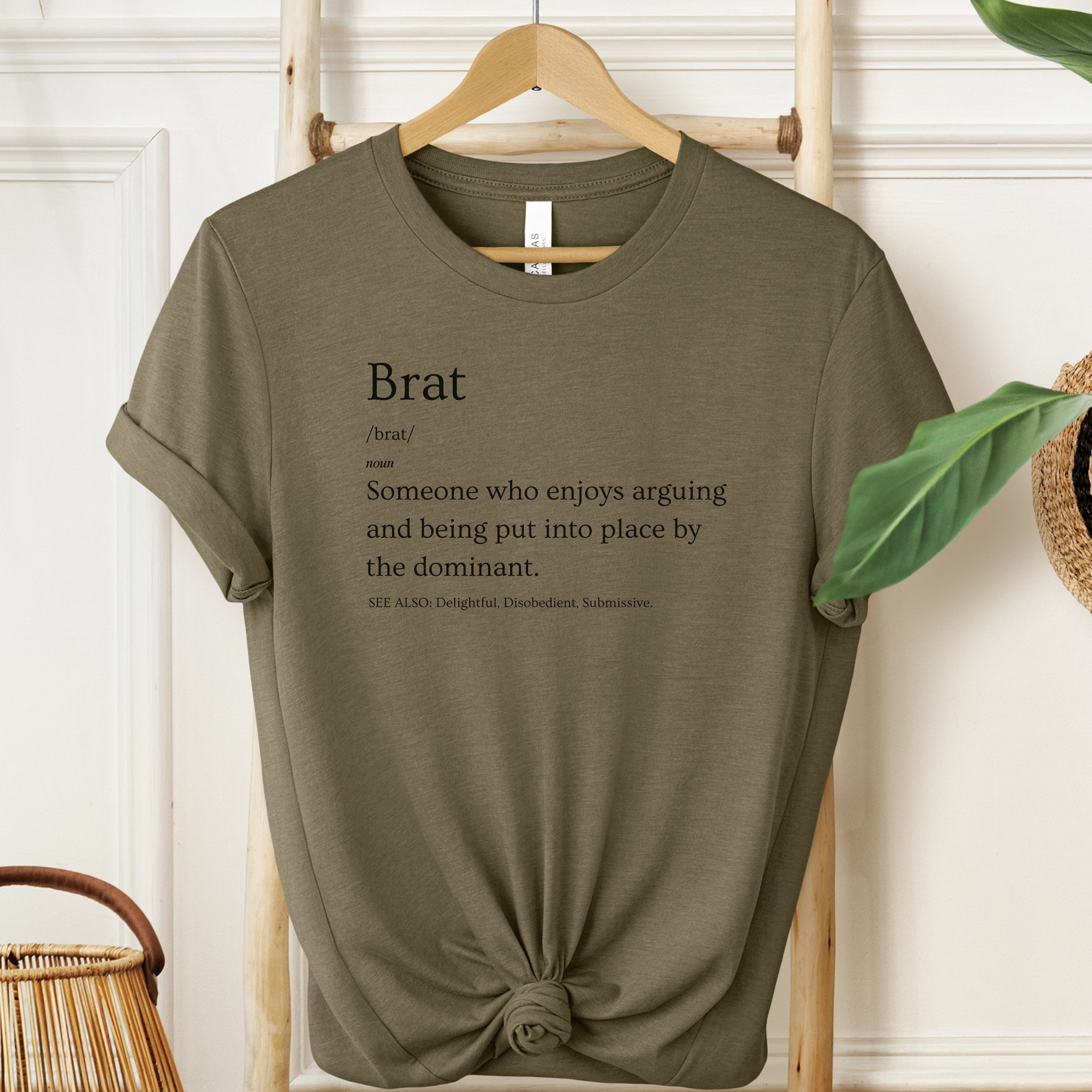 Green t-shirt with text on a hanger against a white wall.