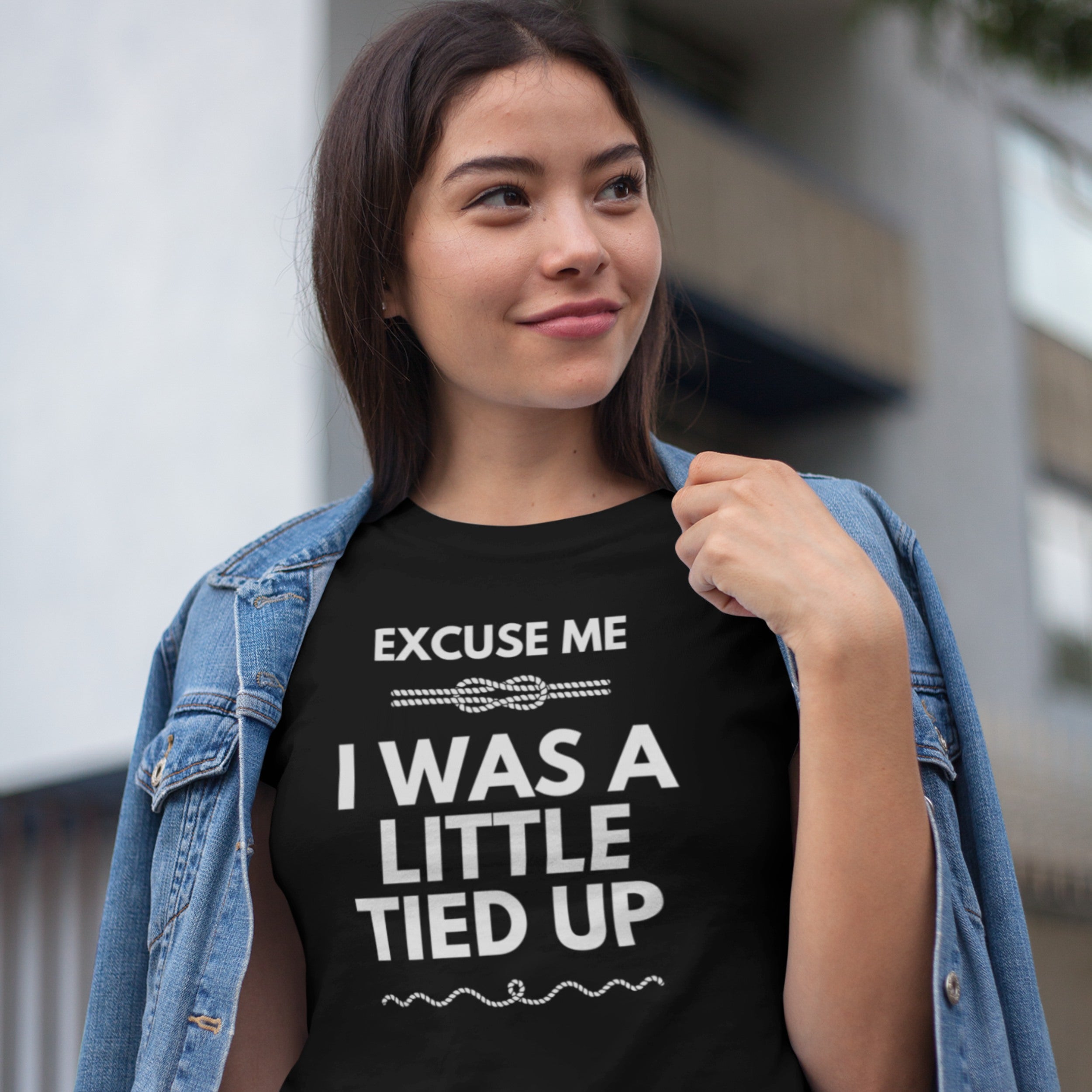 Woman wearing a black t-shirt with text, standing outdoors.