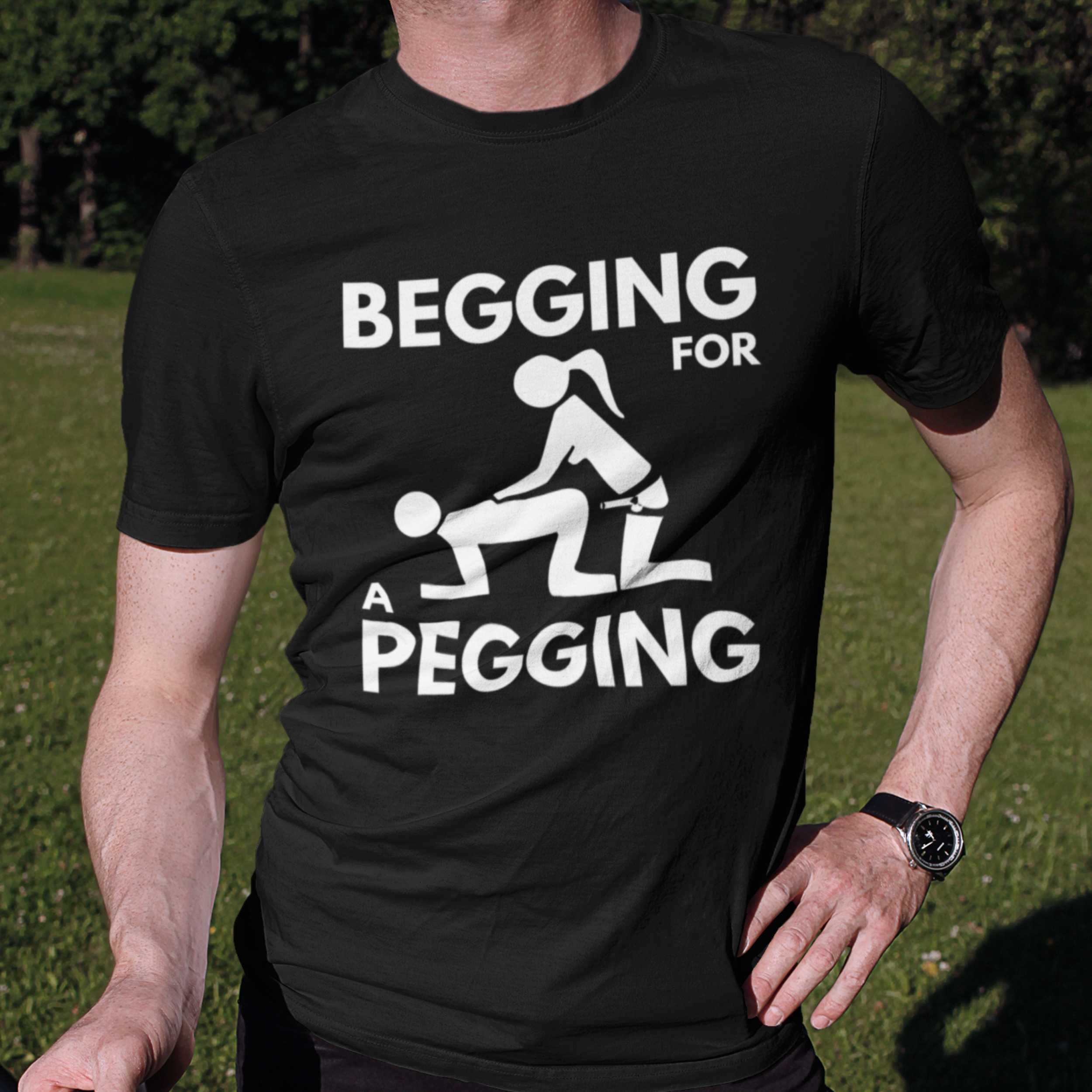 Person wearing a black t-shirt with white graphic and text 'Begging for a Pegging' outdoors.