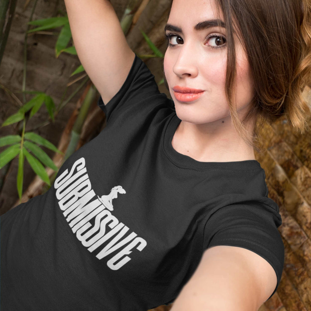 Woman wearing a black t-shirt with 'SUBTLESSIVE' text, standing outdoors with plants in the background.