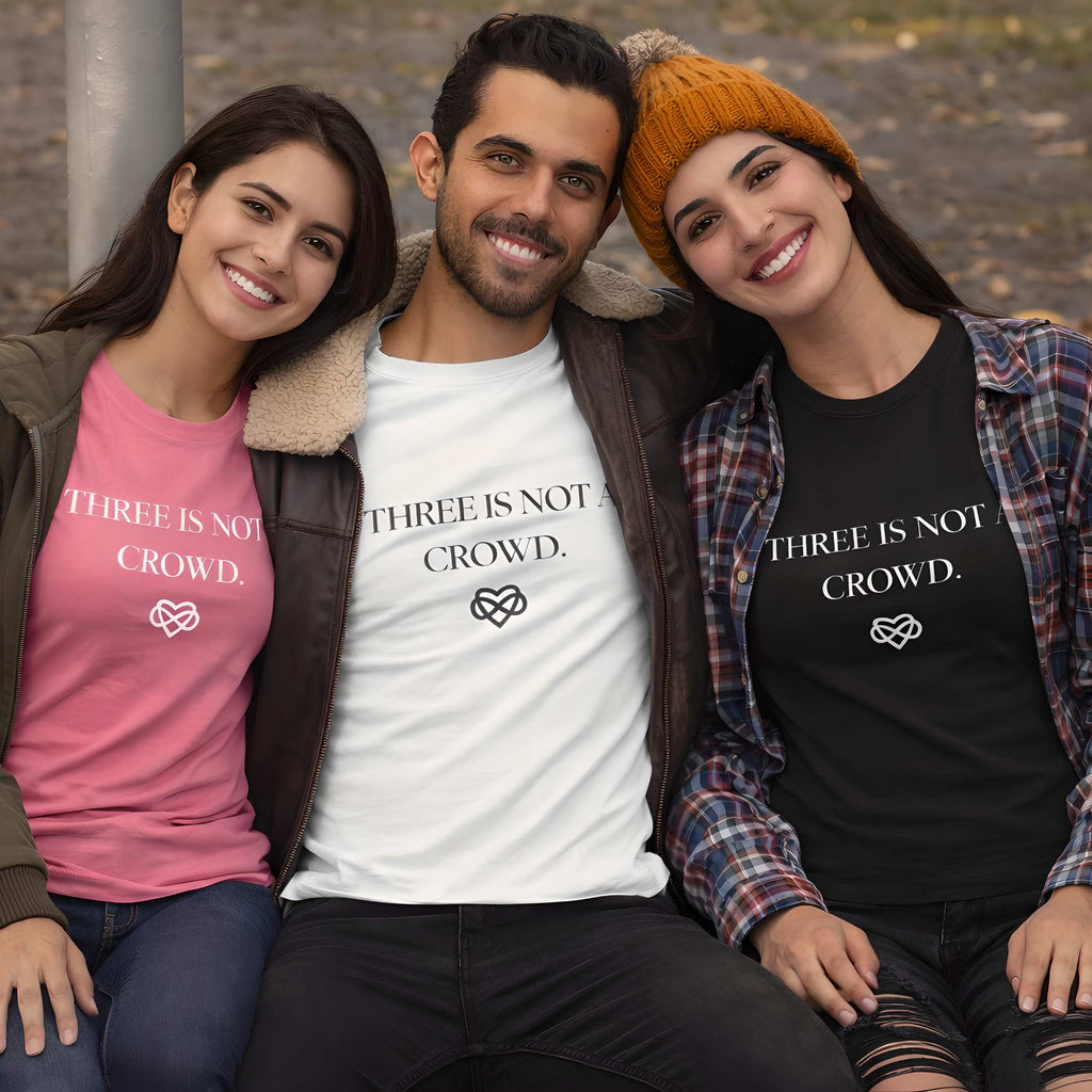 Three people wearing t-shirts with 'THREE IS NOT CROWD.' text, sitting together outdoors.