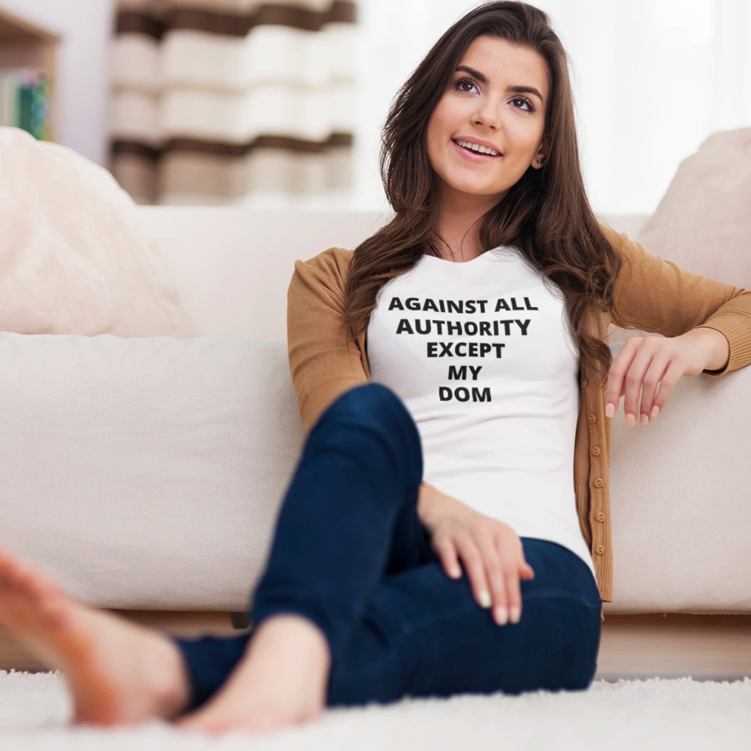 Woman sitting on a couch wearing a t-shirt with text, smiling.