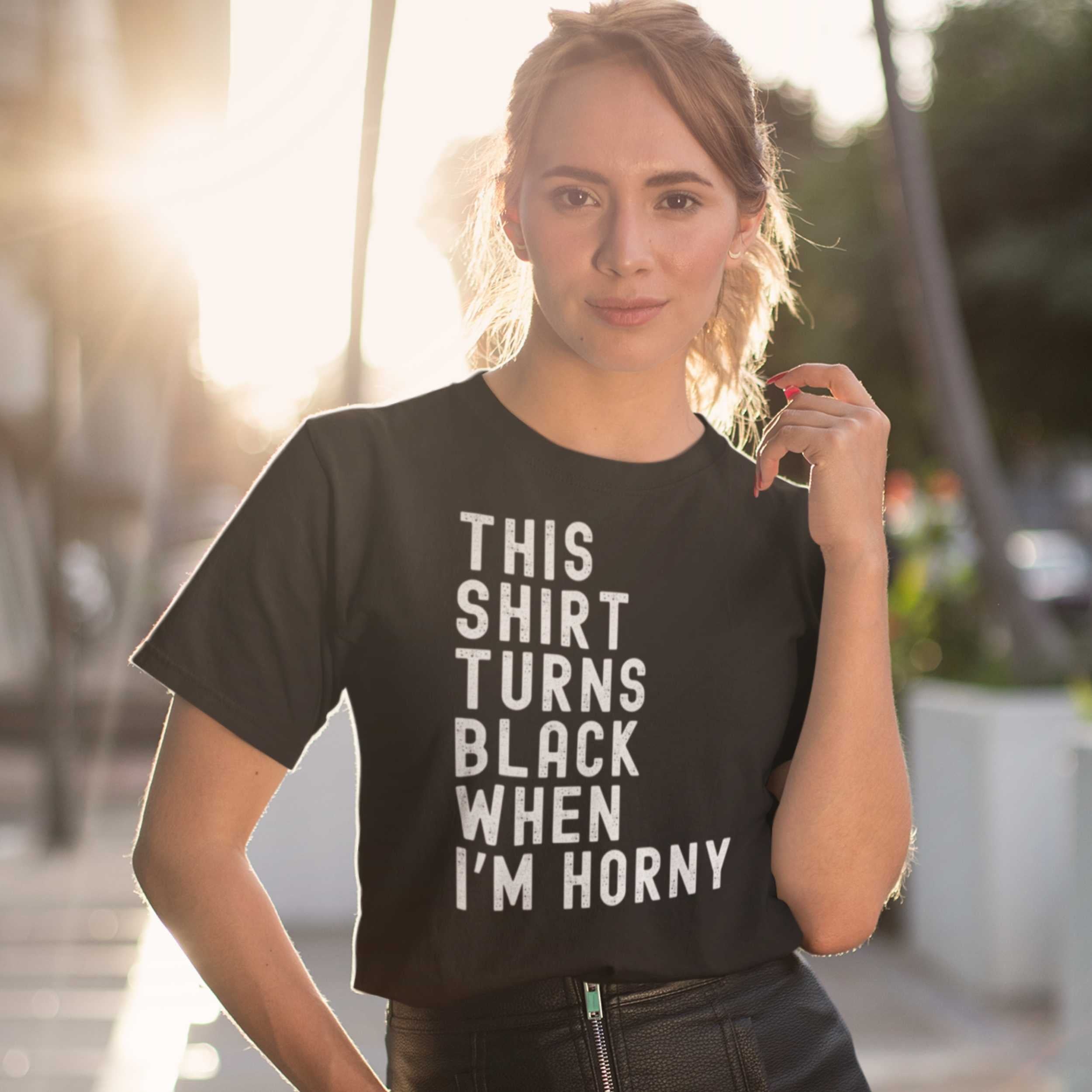 Person wearing a black t-shirt with humorous text outdoors