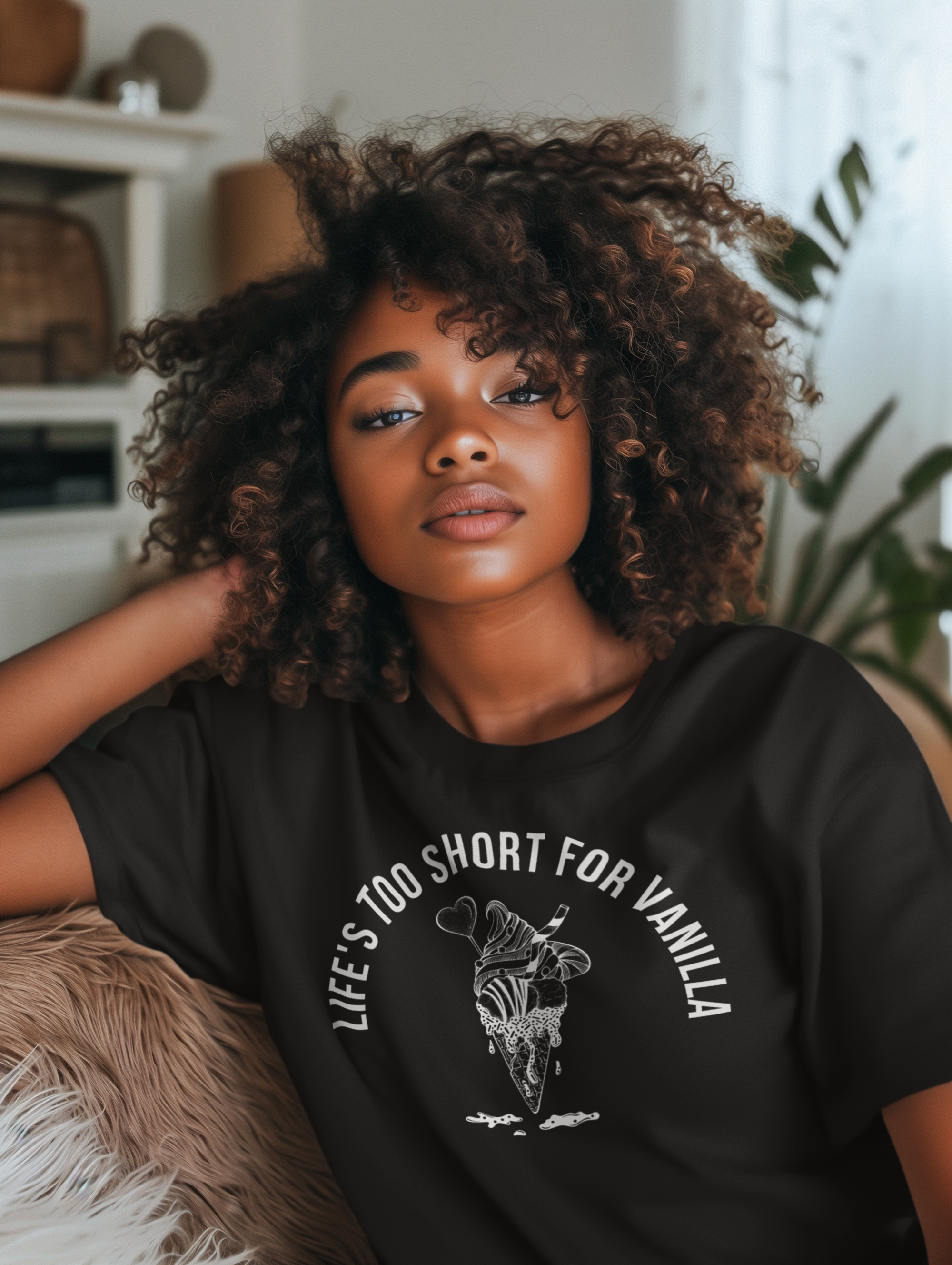 Woman wearing a black t-shirt with a graphic design and text, sitting indoors.